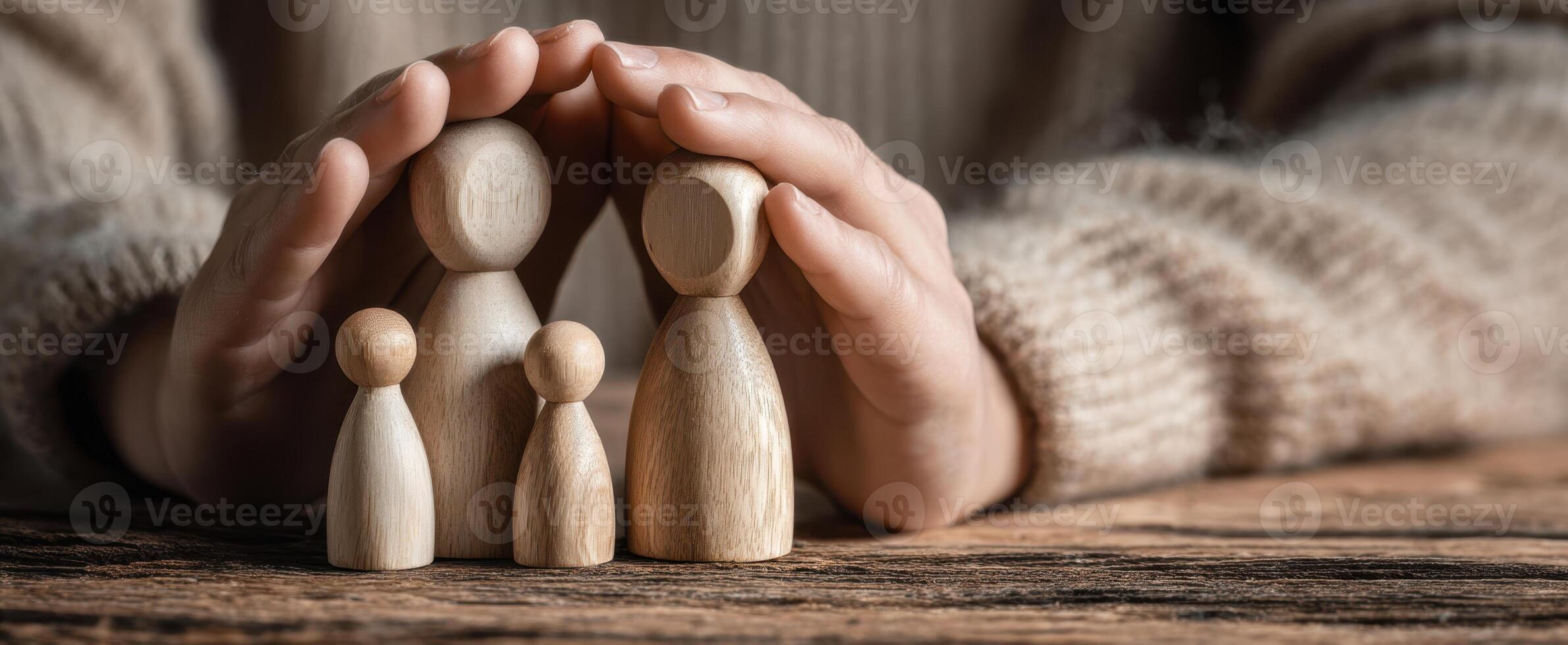 The wooden family figures protected by nurturing hands on a wooden surface photo