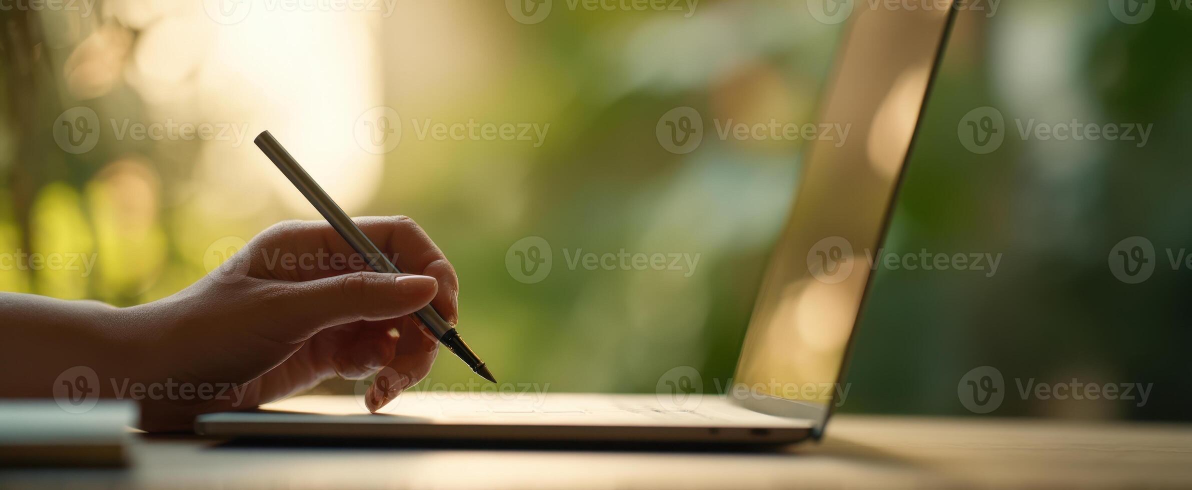 The hand writing on a laptop in a bright, natural workspace setting. photo