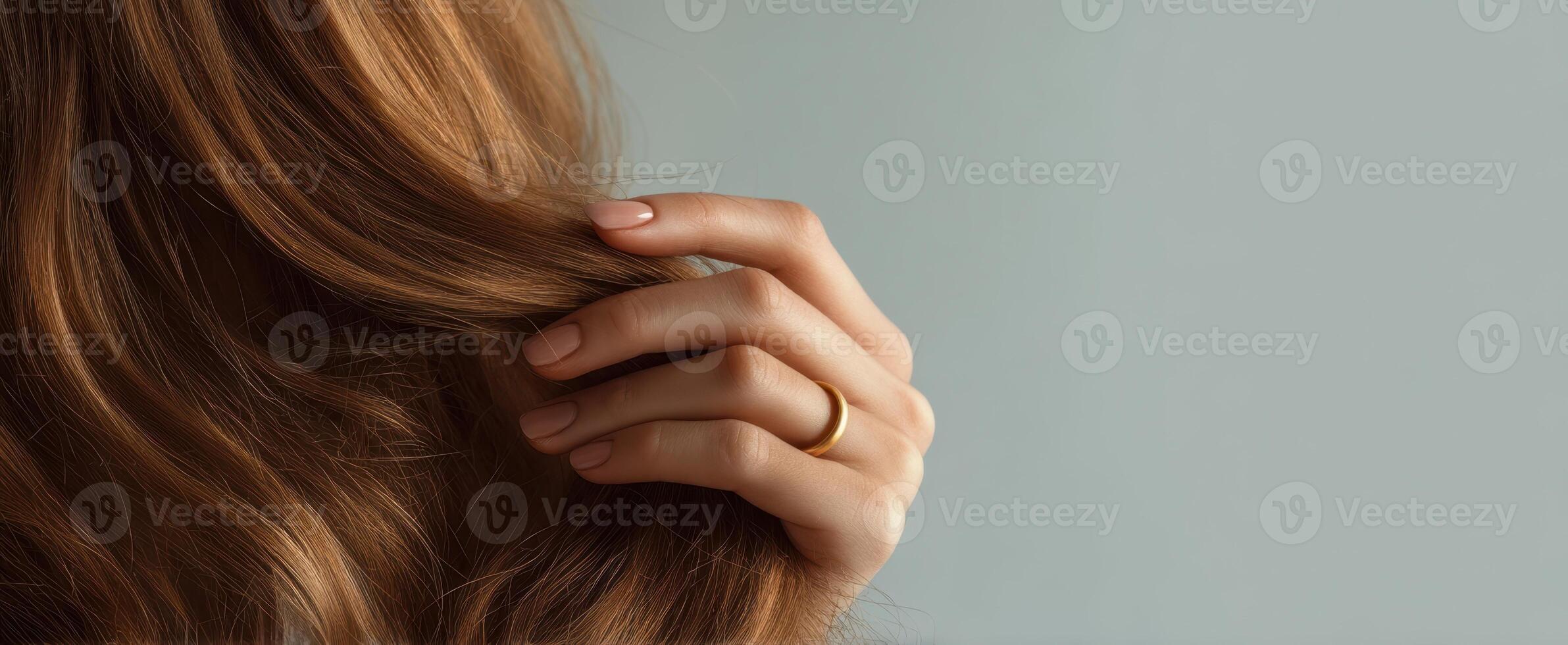 The hand gently holds the flowing hair with a golden ring. photo