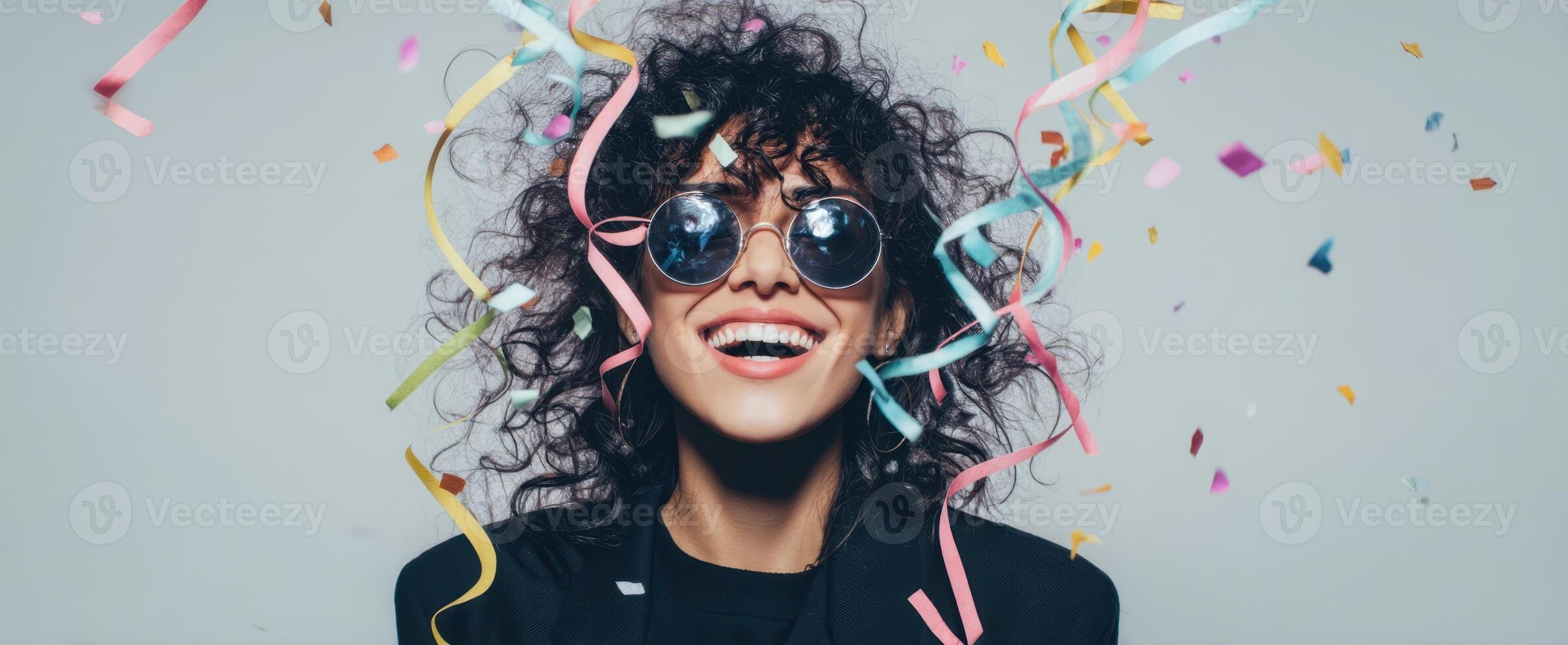 The joyful woman celebrating with confetti and sunglasses in a vibrant atmosphere. photo