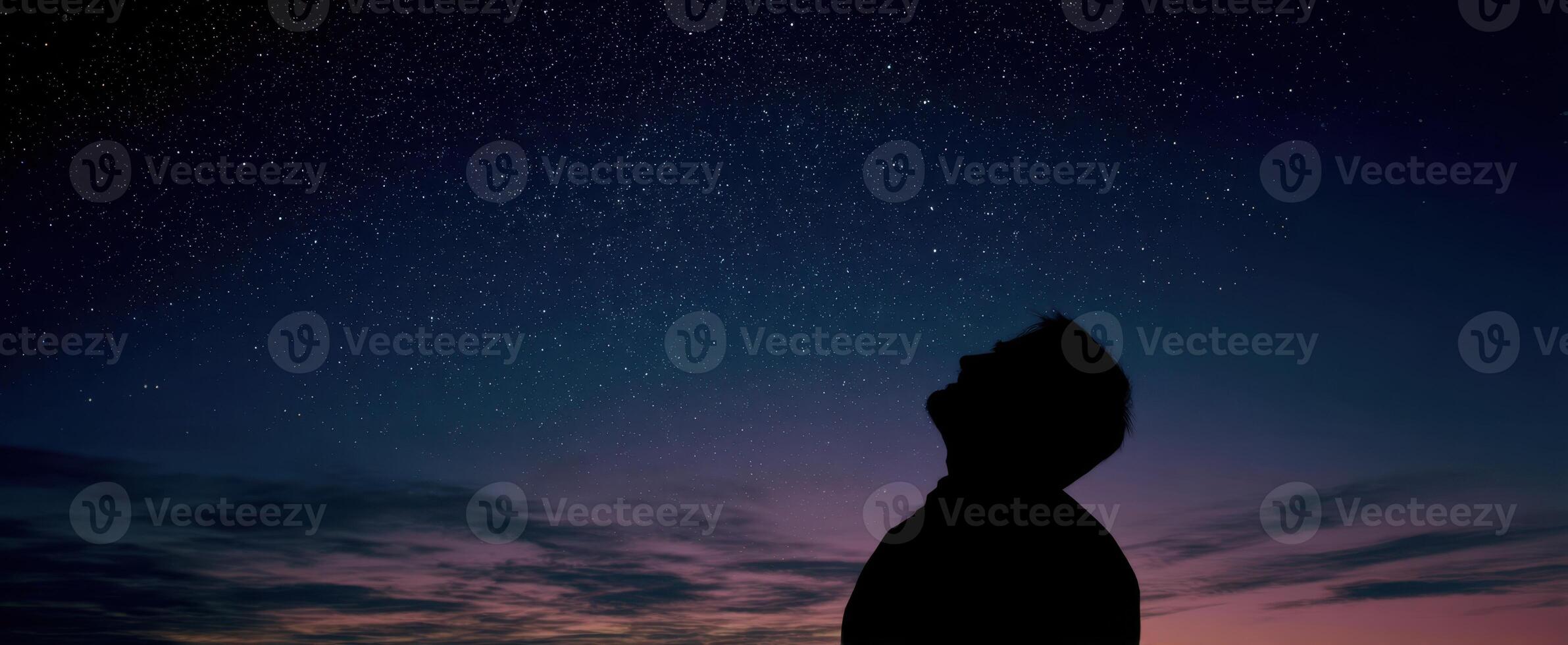 The silhouette of a person gazing at a starry night sky with wonder. photo