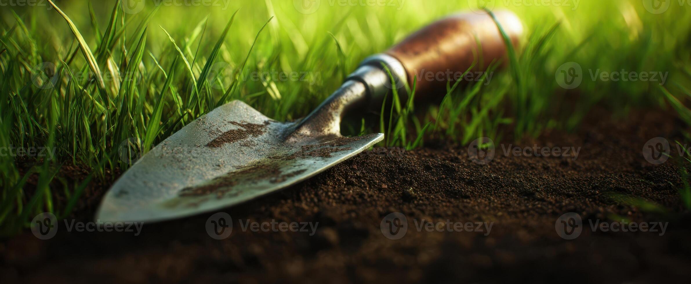 The trowel resting in garden soil amidst vibrant green grass. photo