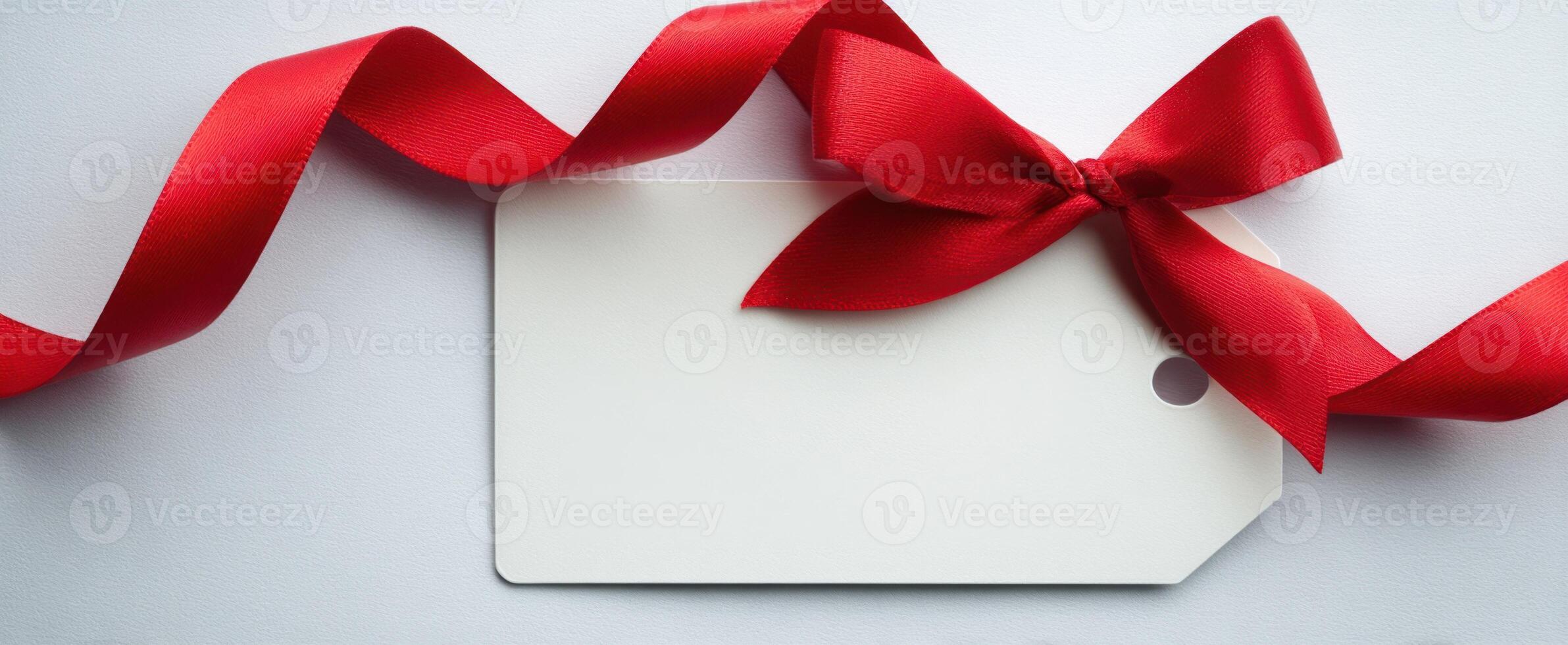 The elegant red ribbon tied to a blank gift tag on a minimalistic background. photo