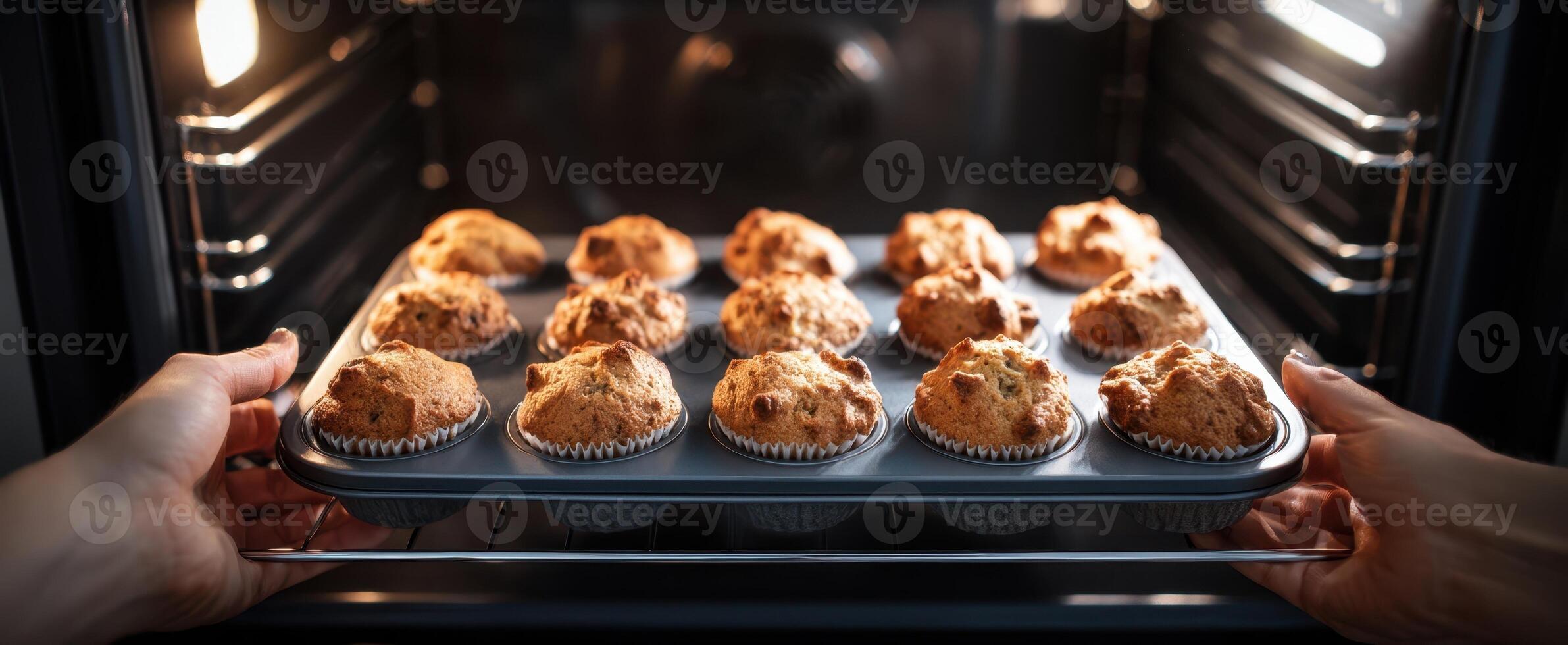 The warm tray of freshly baked muffins being taken from the oven. photo
