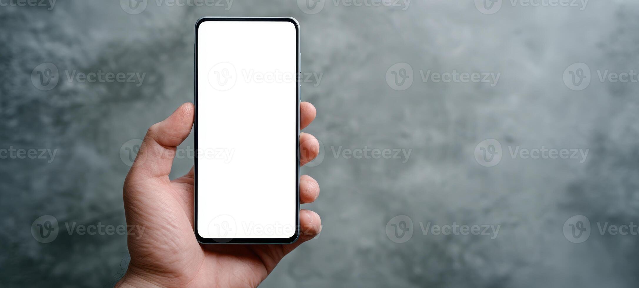 The close-up of a blank smartphone held in a hand against a textured background. photo