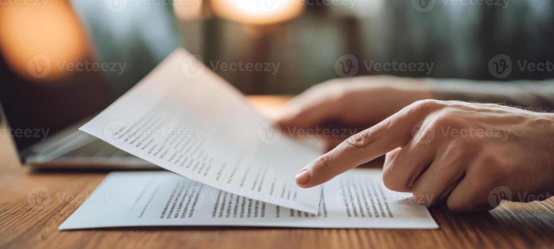 The focused hand reviewing important documents on a wooden workspace. photo