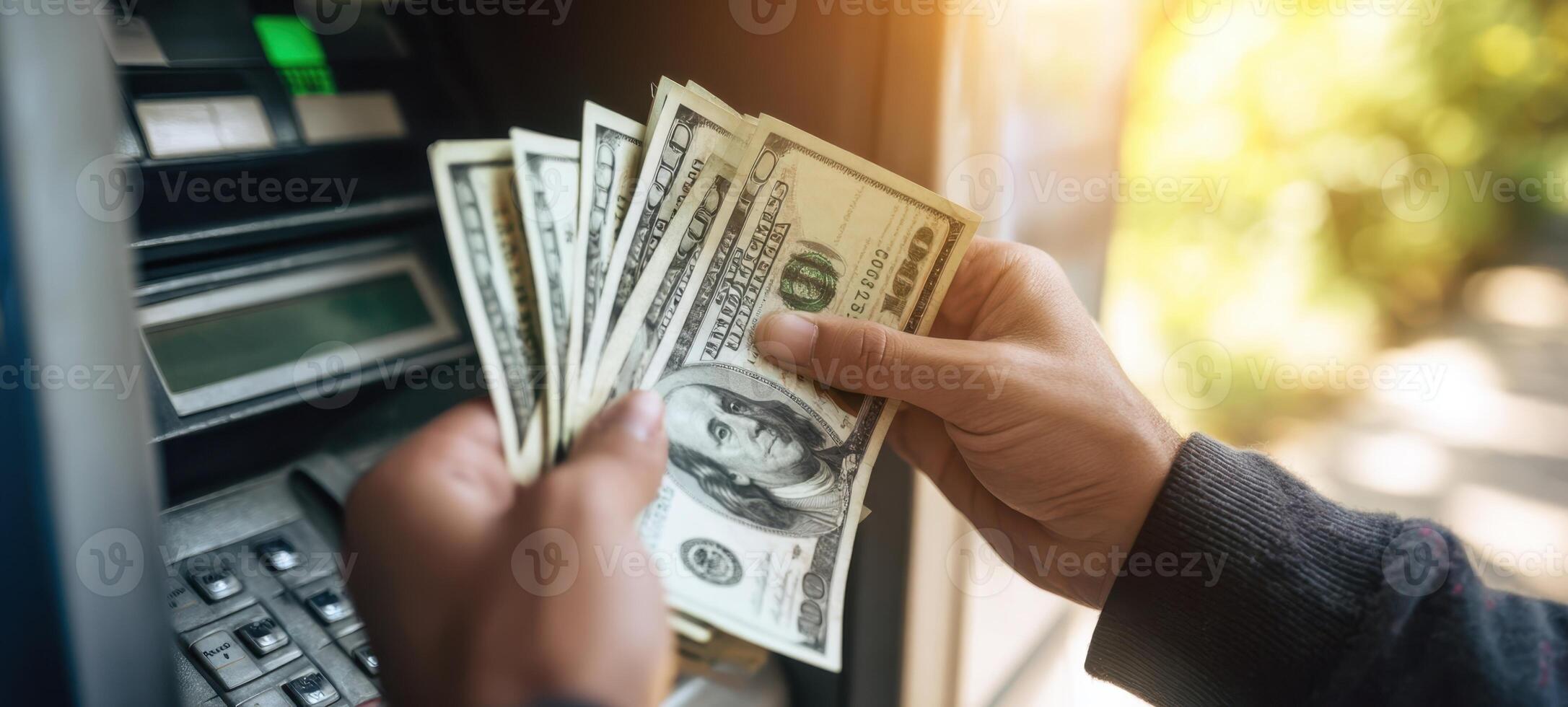 The person holding cash from an ATM while enjoying outdoor sunlight. photo