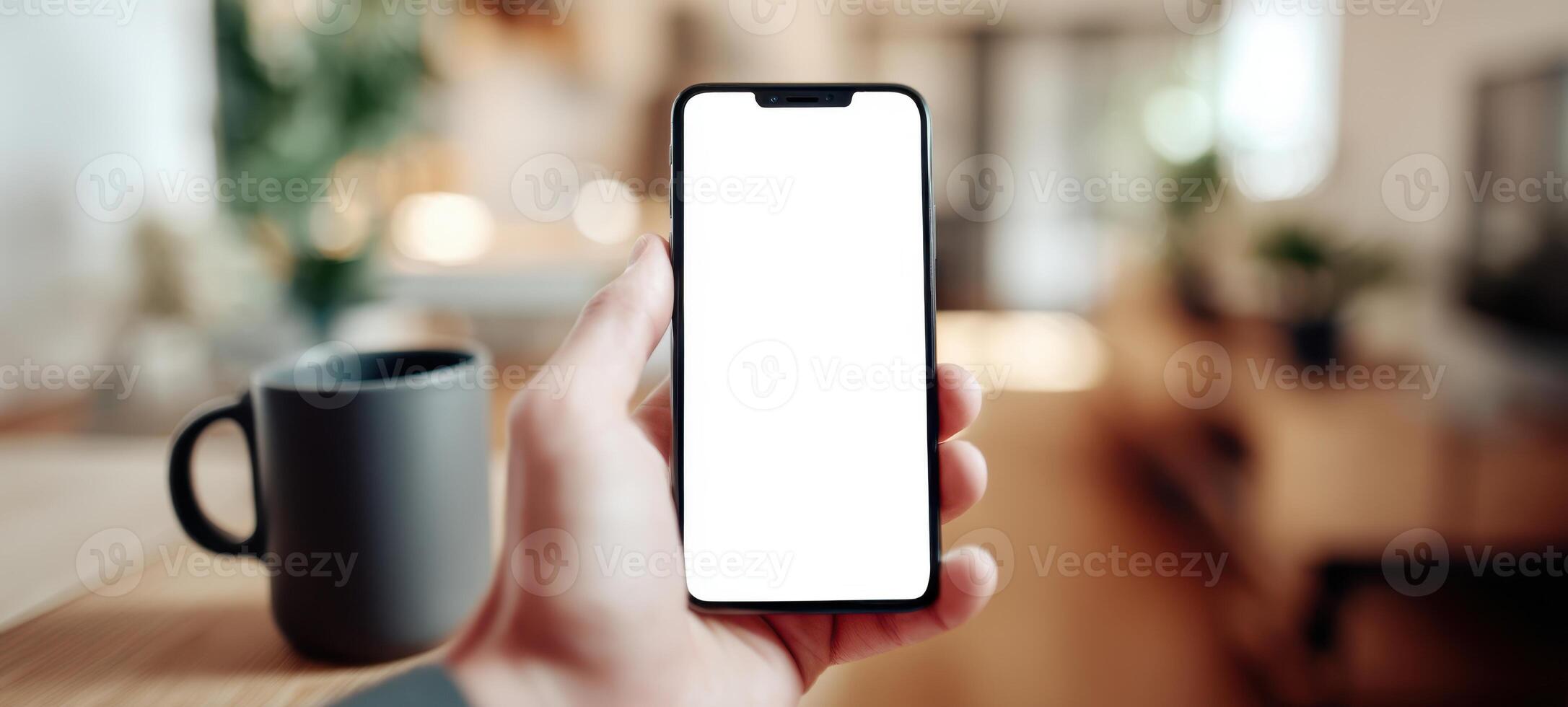 The smartphone held in hand with a blank screen in a cozy environment. photo