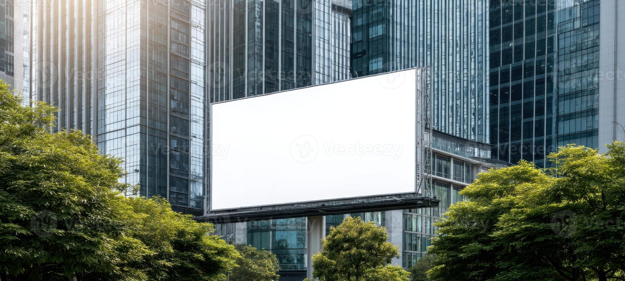 The blank billboard surrounded by modern skyscrapers and lush greenery photo