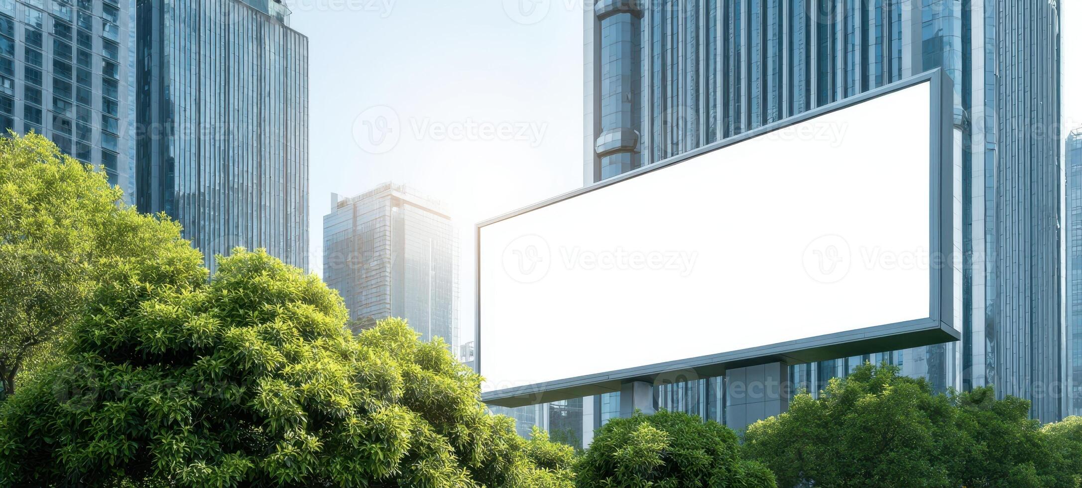 The blank billboard surrounded by lush greenery in a modern cityscape. photo