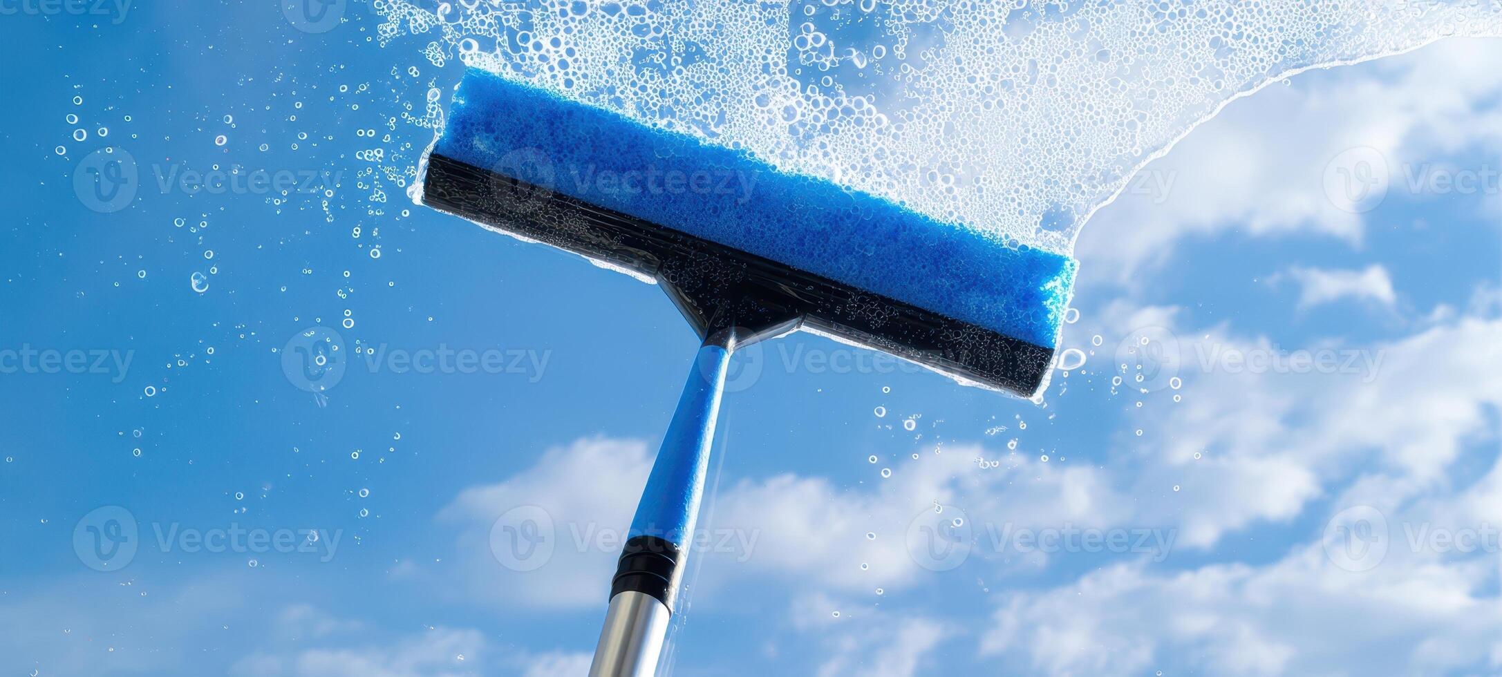 The squeegee glistens with bubbles against a bright blue sky. photo