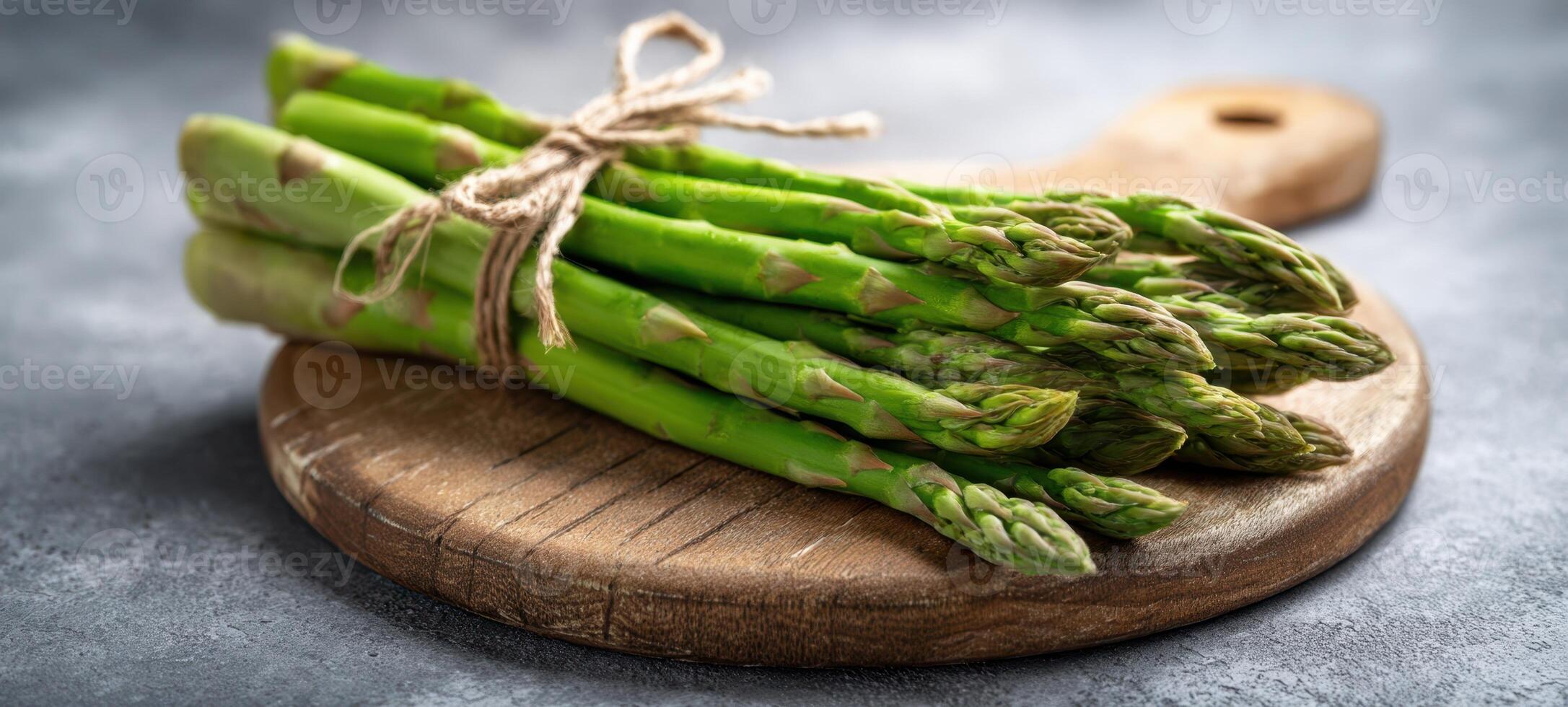 The fresh asparagus tied with string on a rustic wooden board. photo