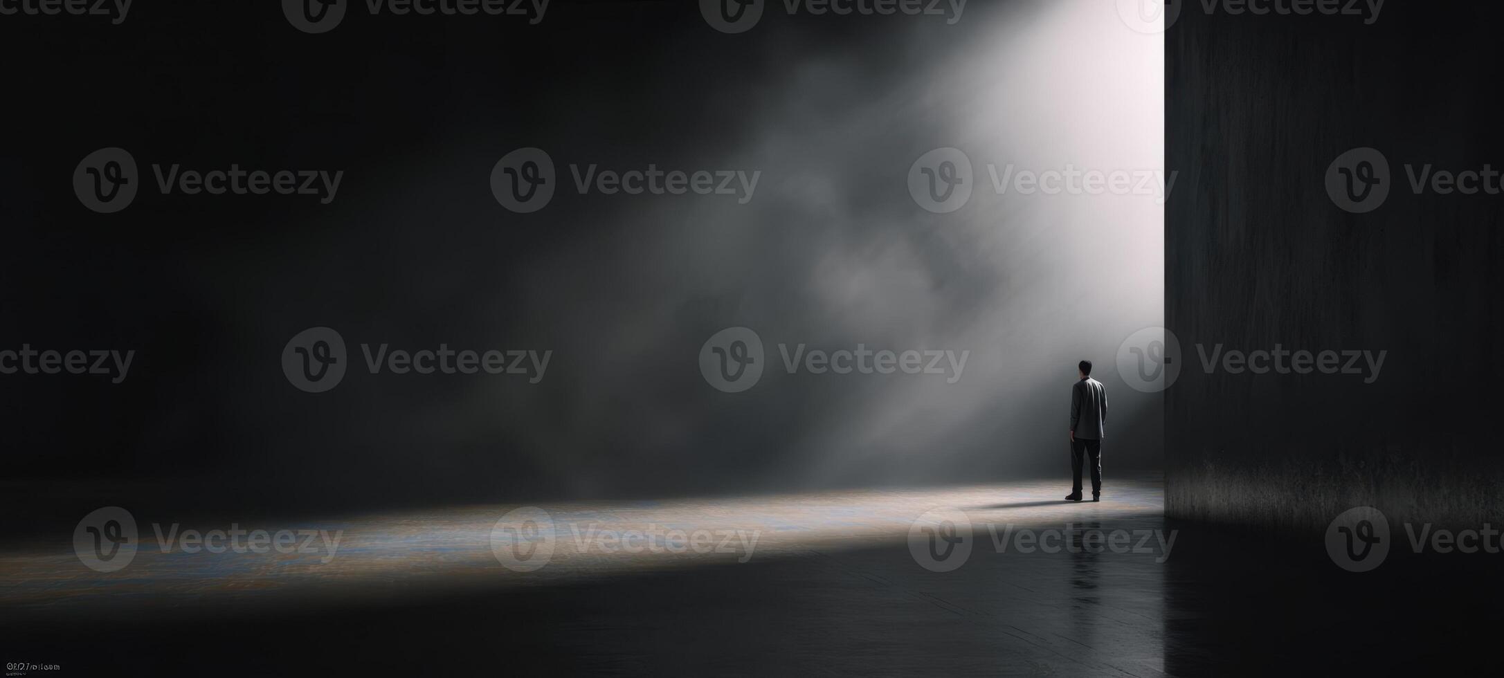 The silhouette of a man standing in a dark, misty space illuminated by light. photo
