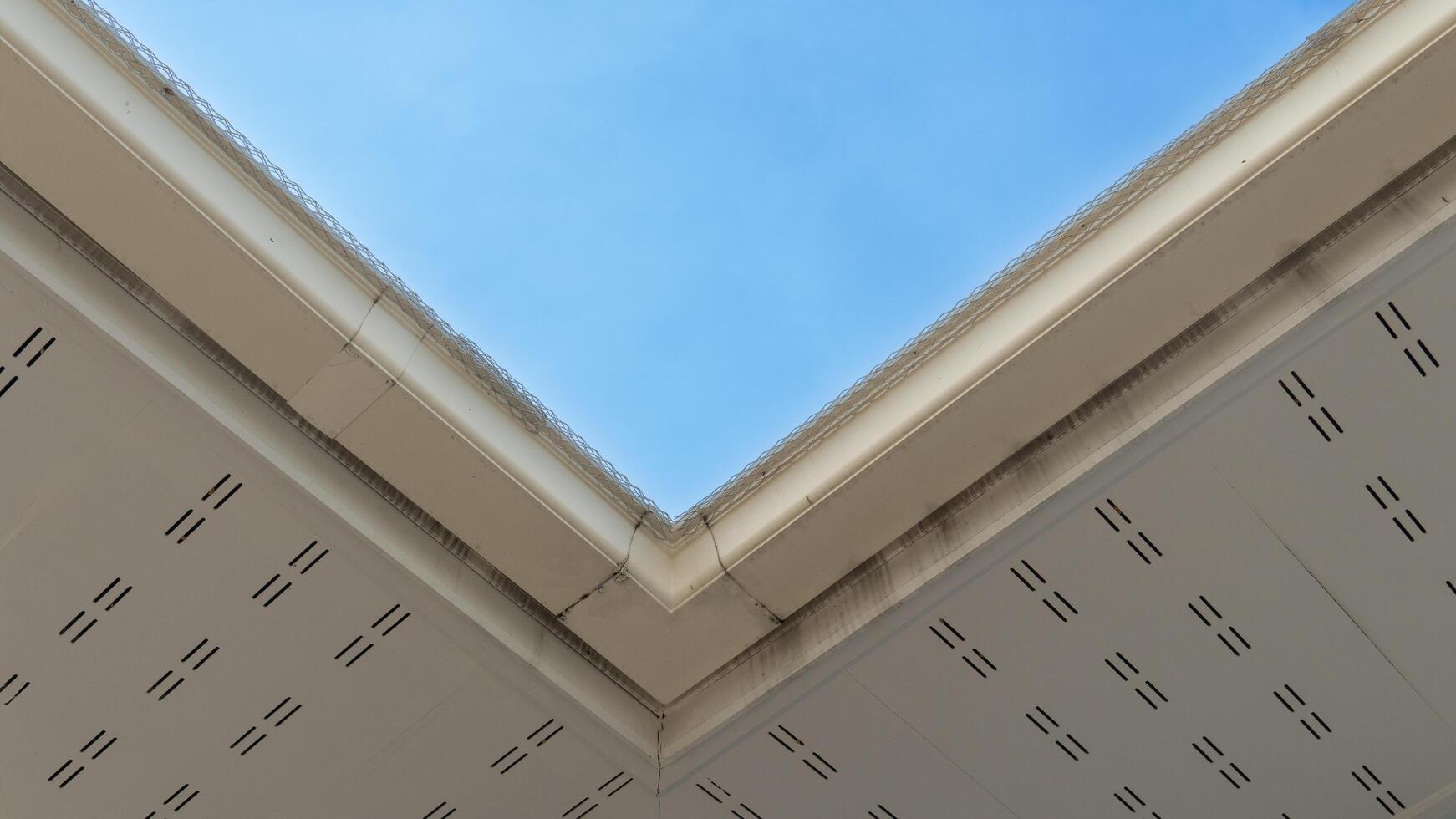 Under view of rooftop. White PVC eaves and drainage channels. background of blue sky. photo