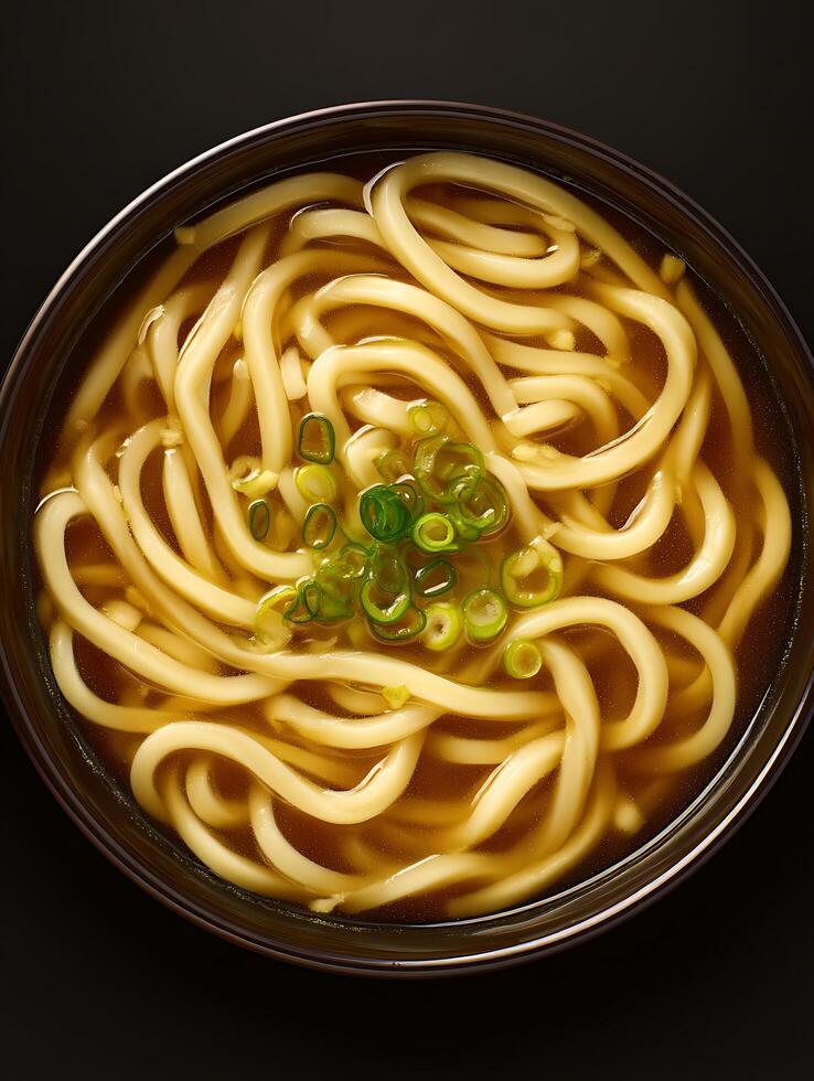 Overhead close up of a bowl of udon noodle soup with green onions. photo