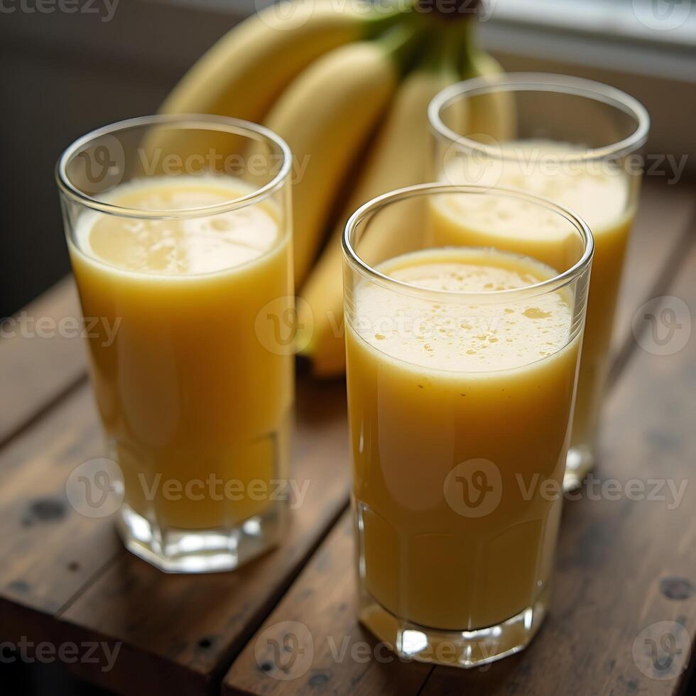 Banana Juice in Glasses with Fresh Bananas on a Wooden Table photo