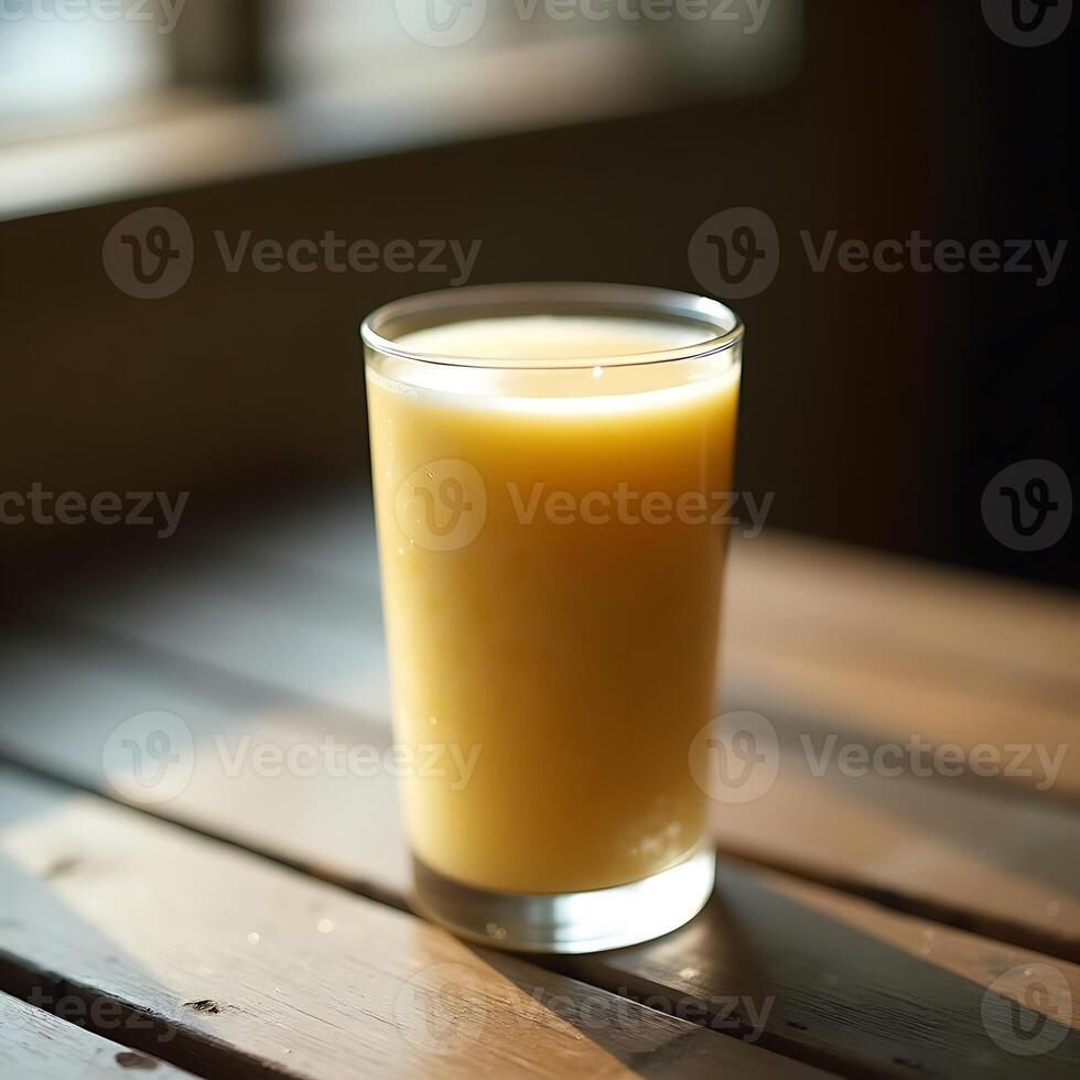 Glass of Orange Drink on Wooden Table in Sunlight photo