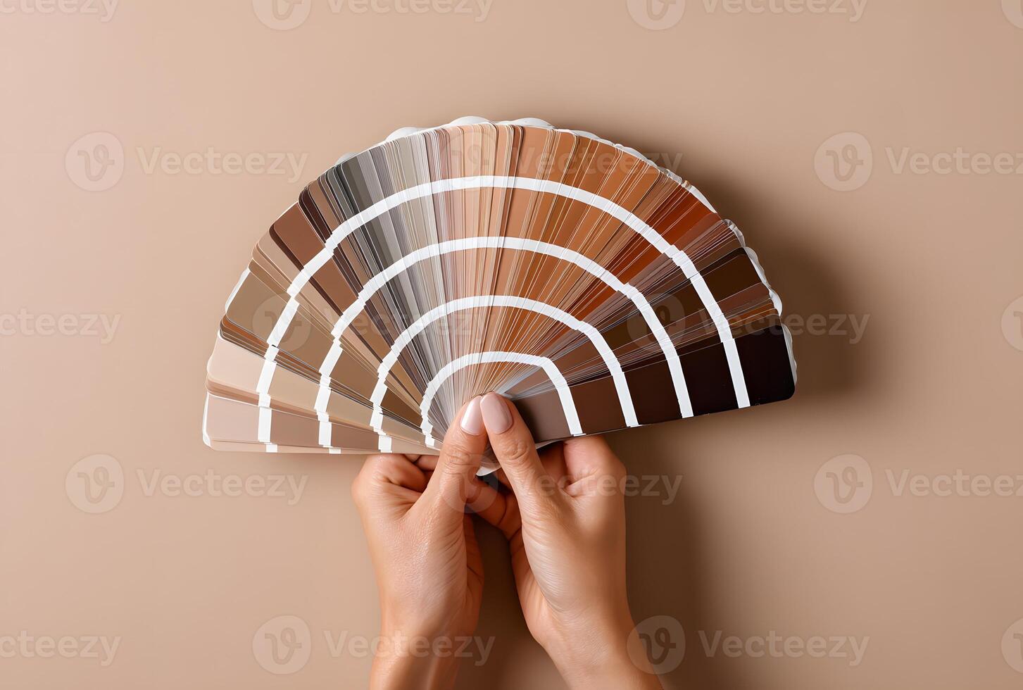 A color palette fan spread by hands against a neutral background. photo