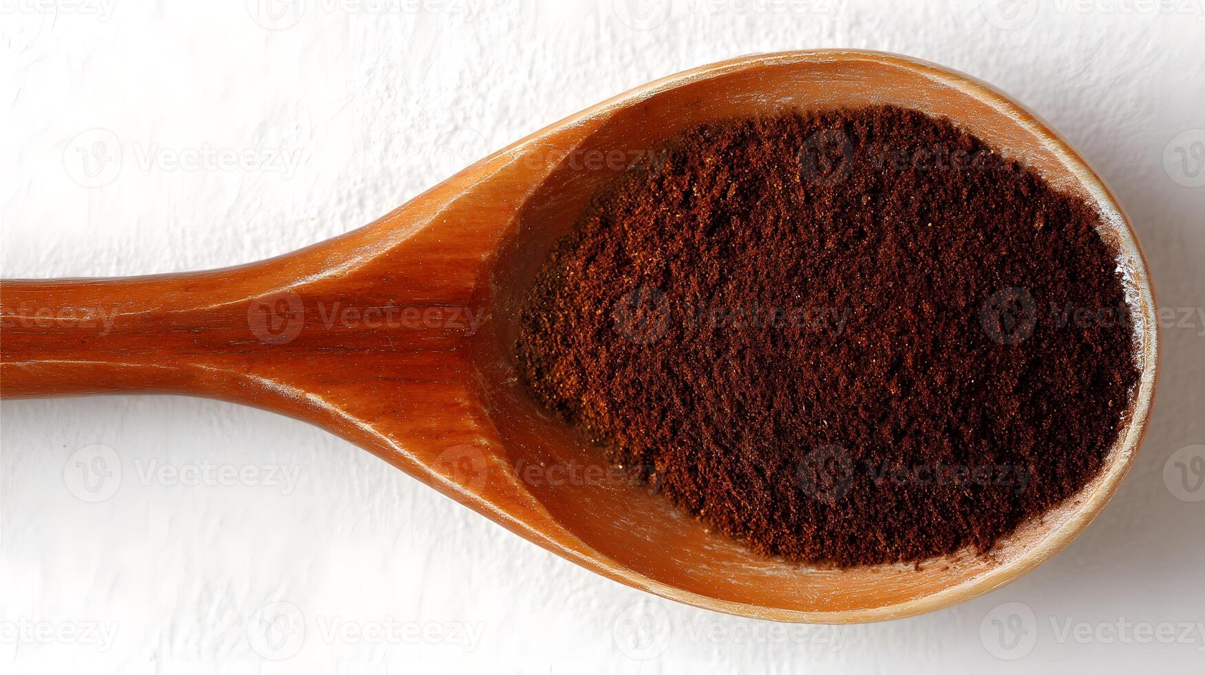 Dark brown spice powder in a wooden spoon. photo