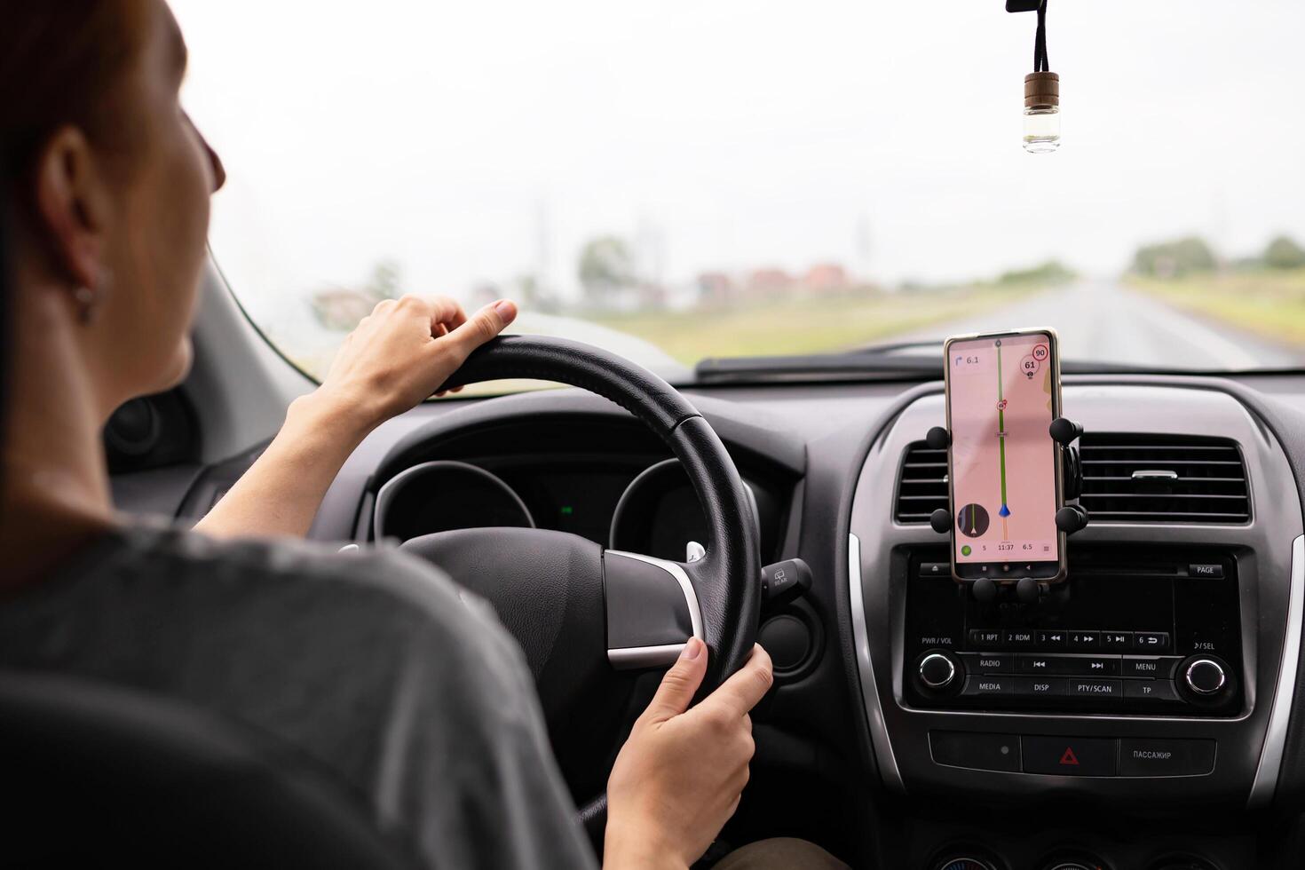 Rear view of a young traveler on a mobile phone behind the wheel of a modern car . photo
