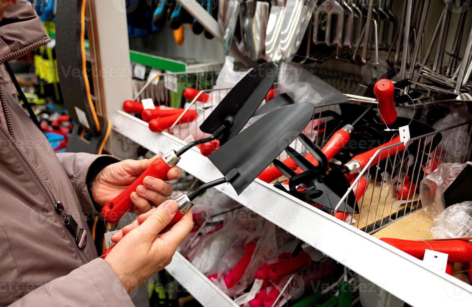 Person examining gardening tools in a hardware store. photo