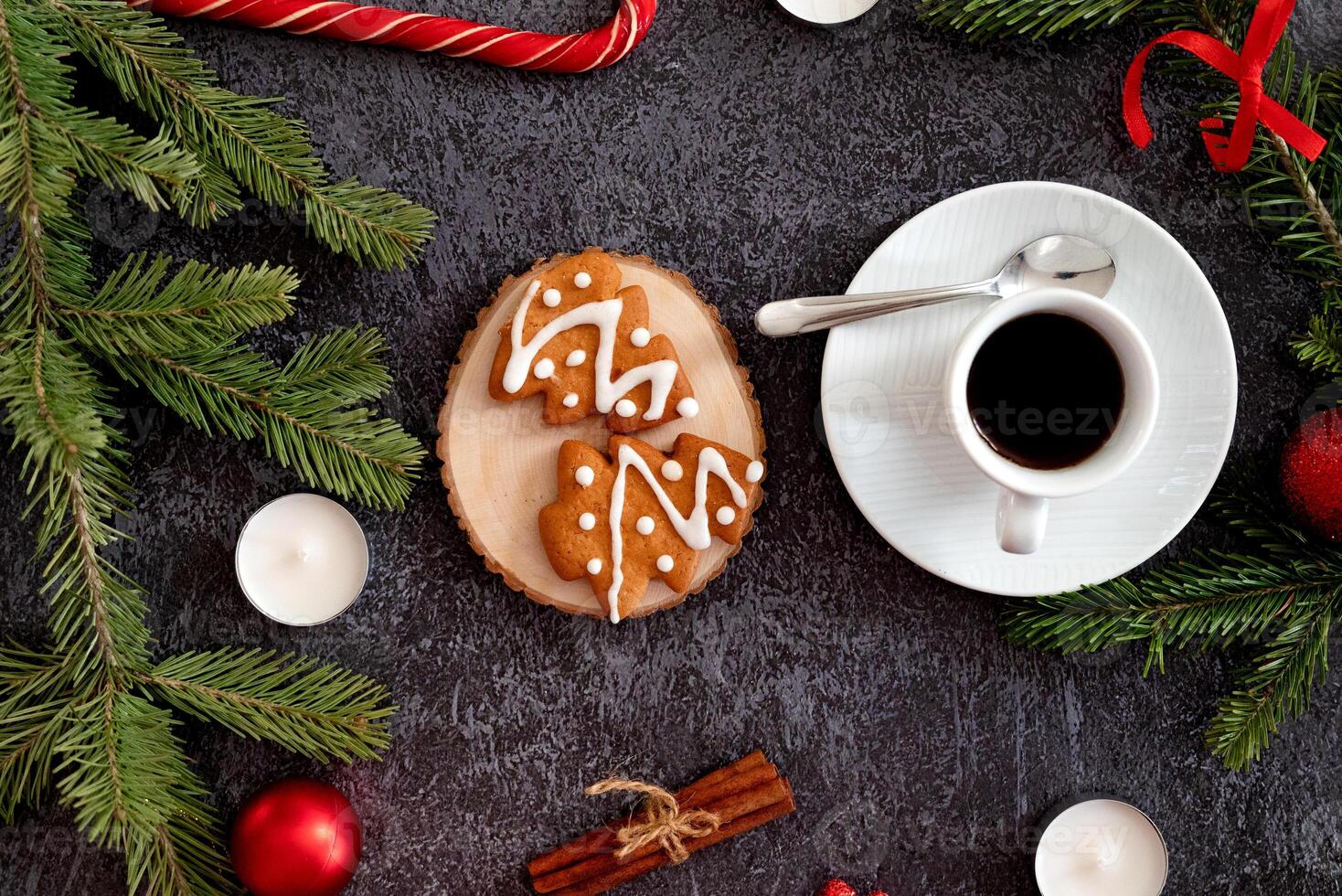 An aesthetic Christmas flat lay composition on a dark backdrop, highlighting heart-shaped candy canes, gingerbread trees, photo