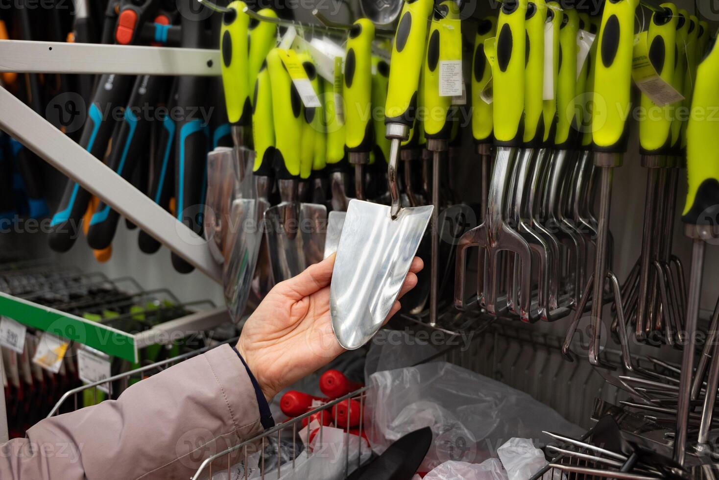 Person examining gardening tools in a hardware store. Handles product. photo