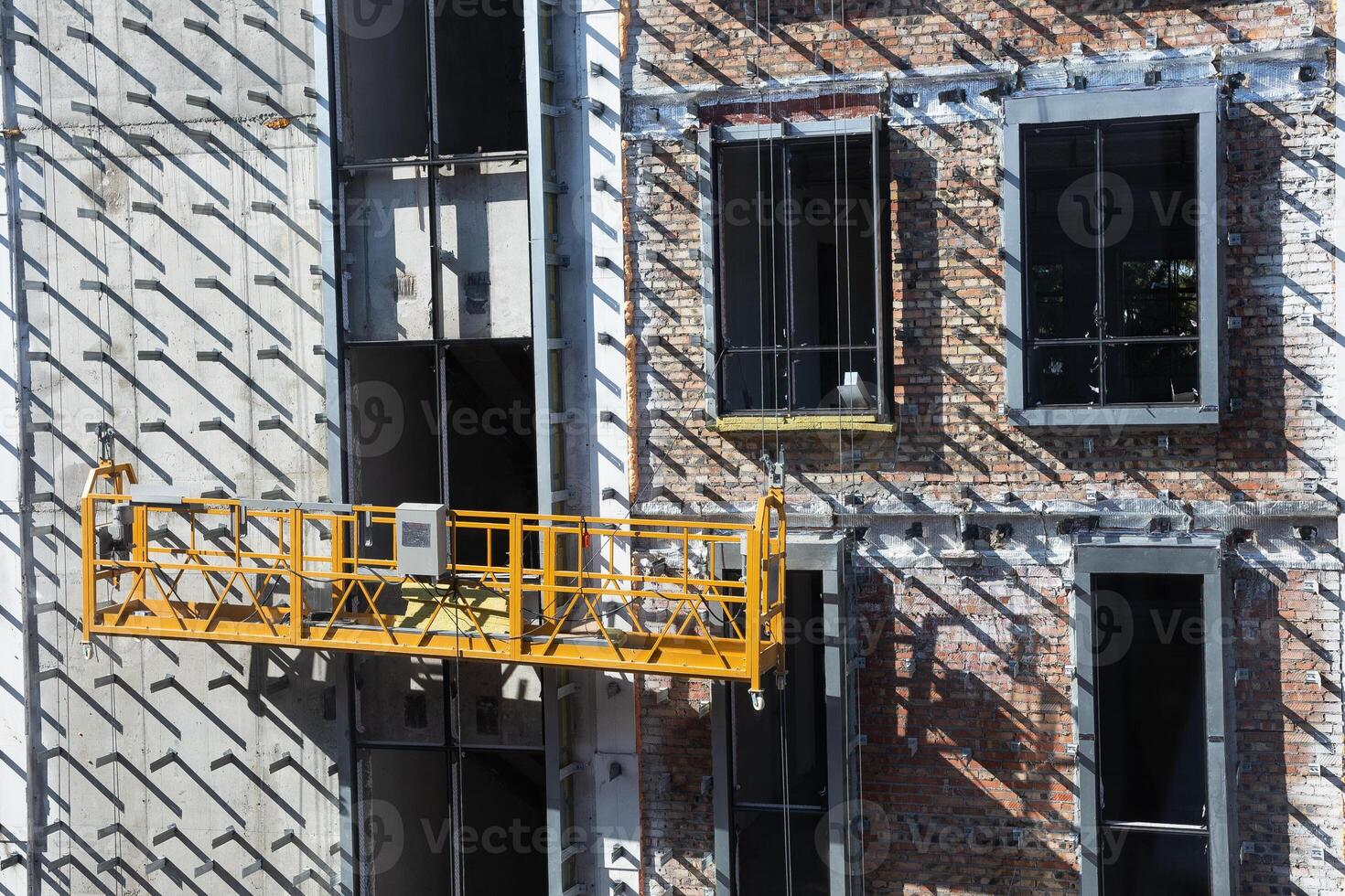 Construction site with hanging scaffold on brick building facade. photo