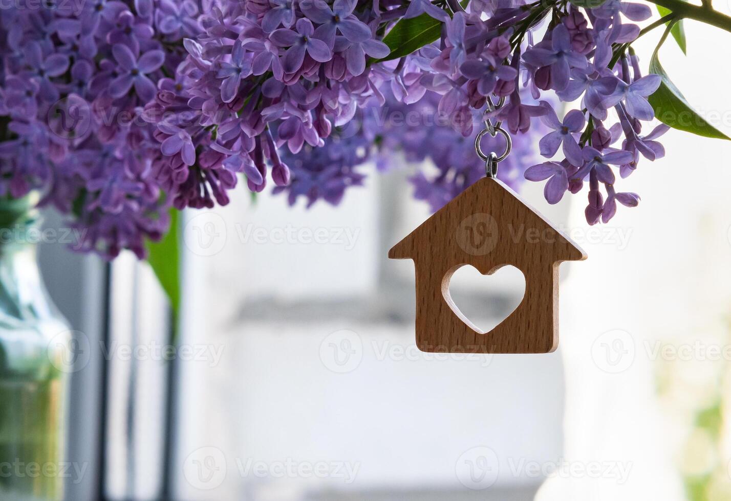 keys and keychain in the form of a house against a background of lilac, a symbol of the family hearth and own home. Purchase of real estate. photo
