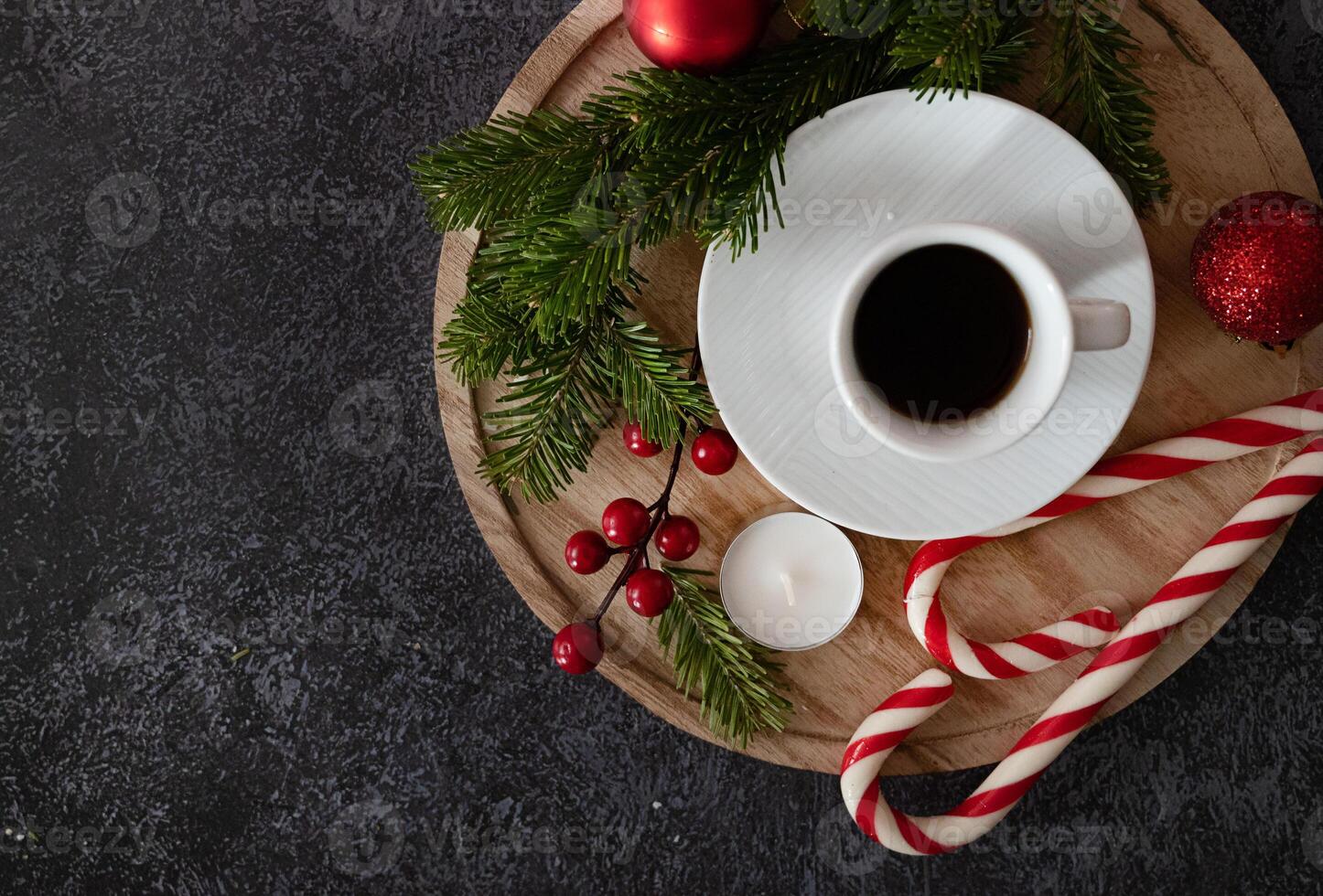 An overhead view of a Christmas-themed flat lay with a coffee cup, gingerbread cookies, cinnamon, candy canes, candles, and pine branches, beautifully arranged to create a warm, holiday atmosphere. photo