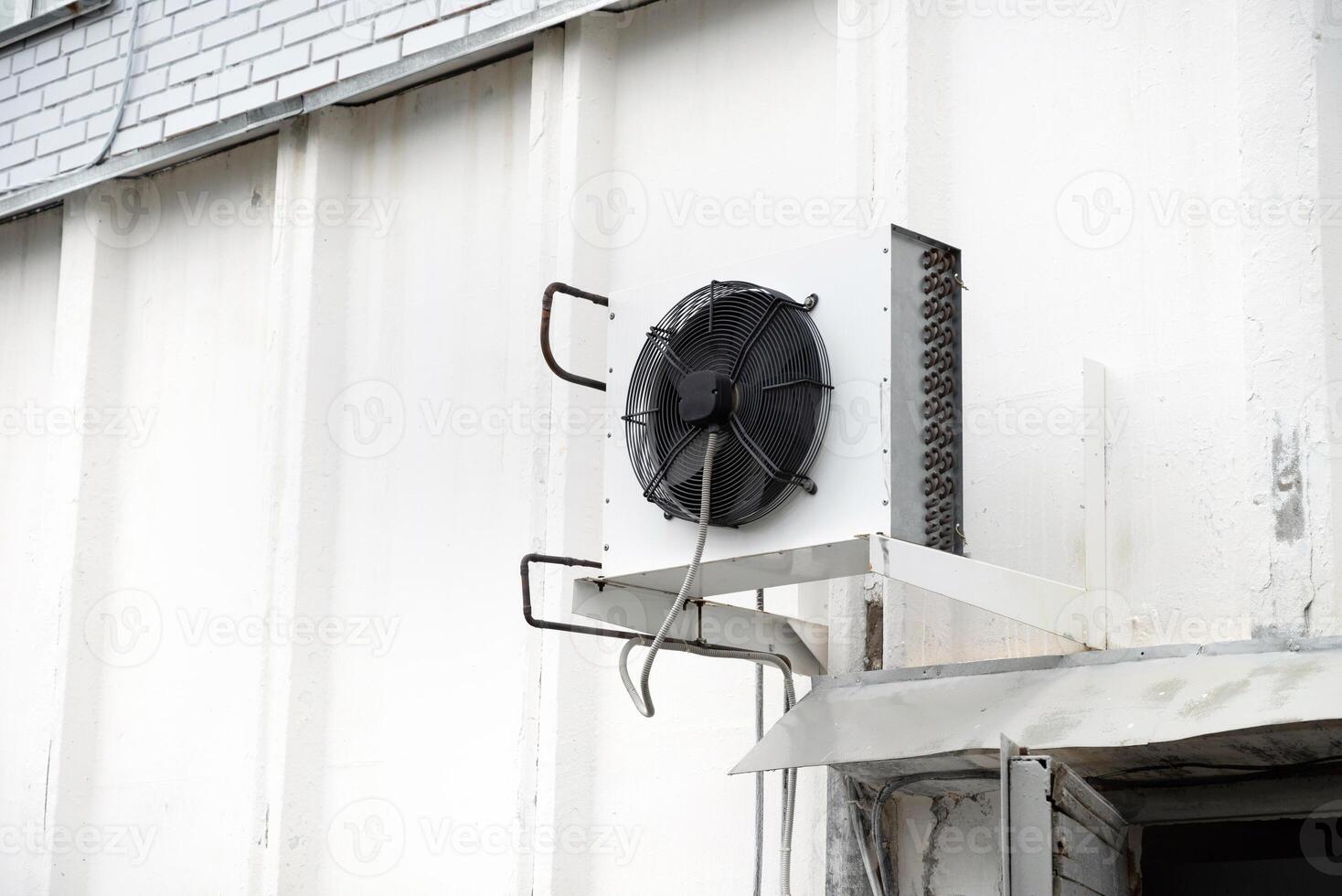 Industrial air conditioning unit mounted on white wall. Temperature control. photo