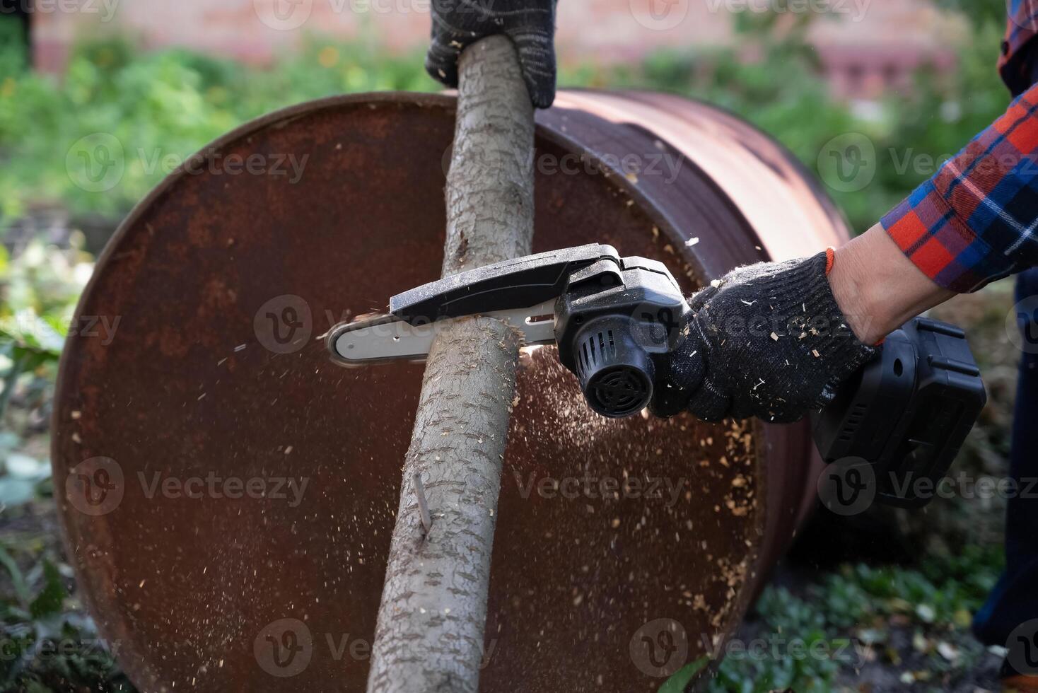 A man in gloves saws a wooden tree trunk with a saw. professional working. photo