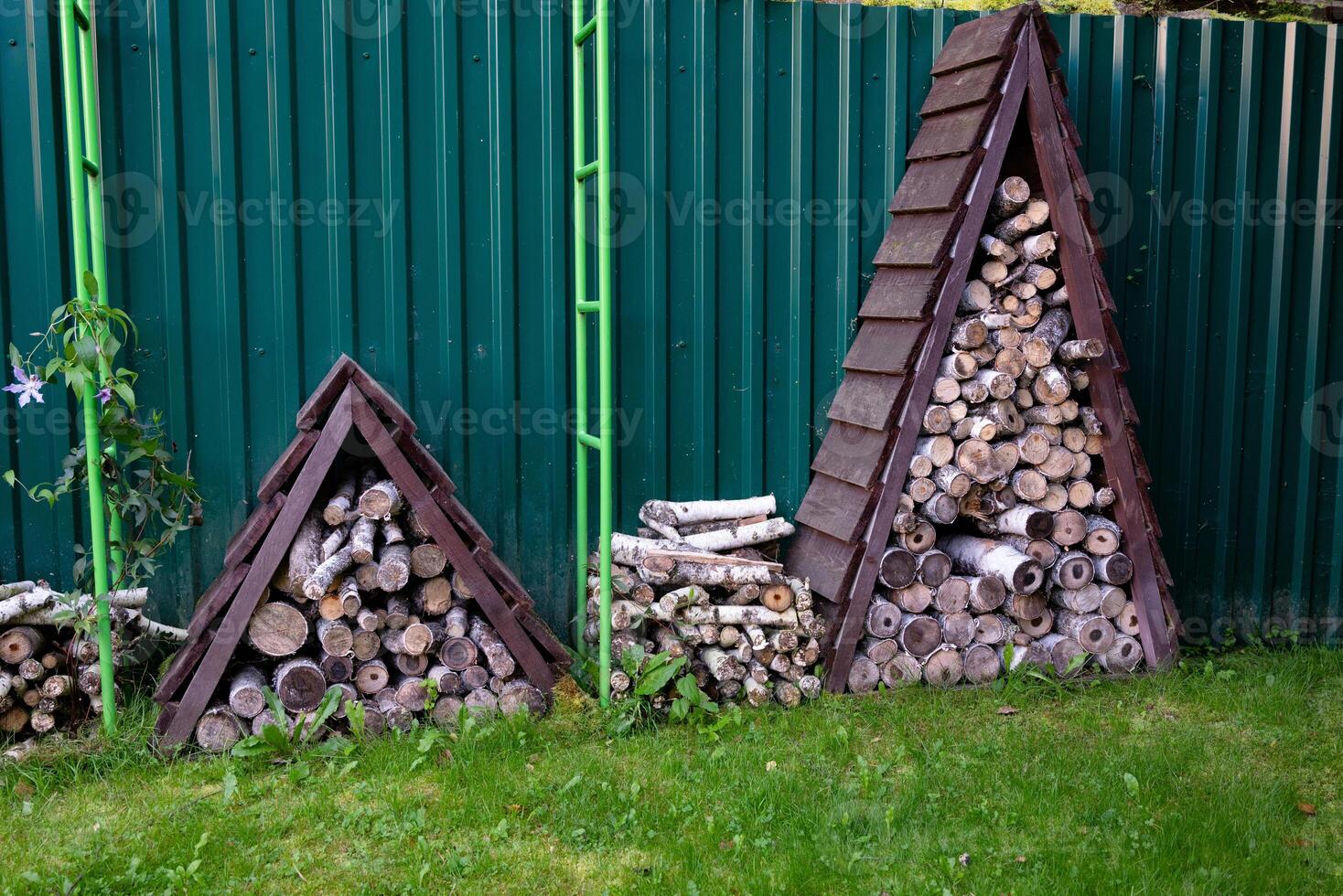 Stacked firewood in wooden shelter in garden.. photo