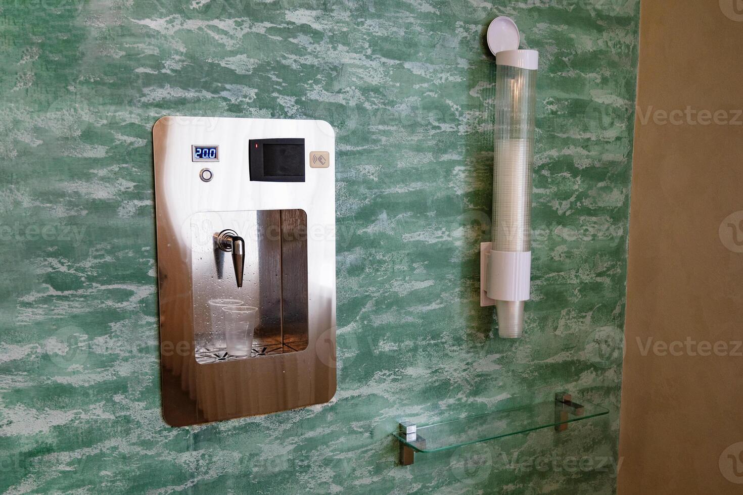 Close-up of water dispenser with a plastic cup filled with mineral water. photo