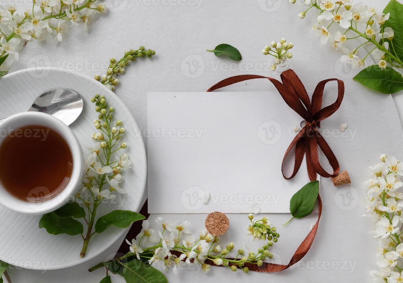 A white cup filled with tea is placed on a matching white saucer. photo