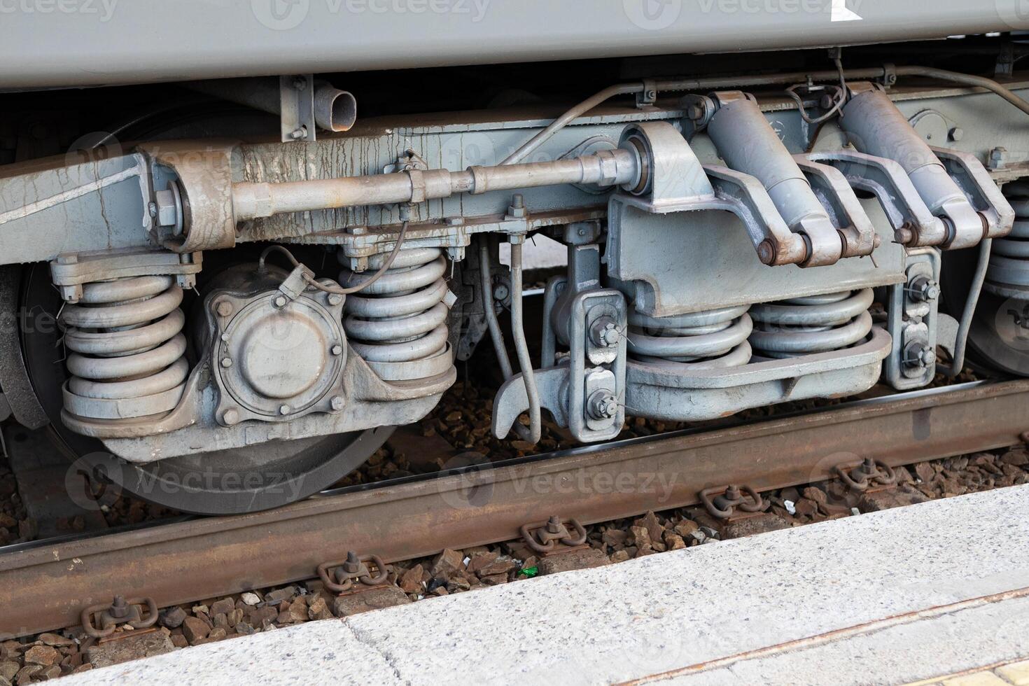 Detailed view of train undercarriage showcasing suspension system and wheel assembly at a railway station photo