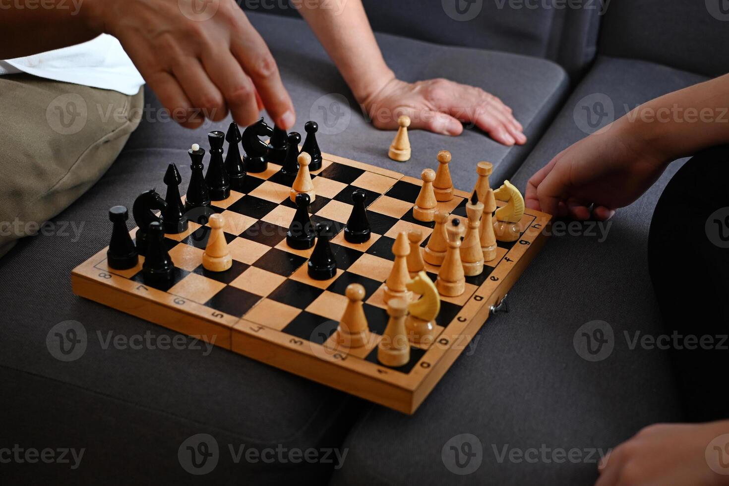 a teenage granddaughter are enthusiastically playing chess on a cozy sofa, demonstrating strategy and concentration in a cozy living room environment photo
