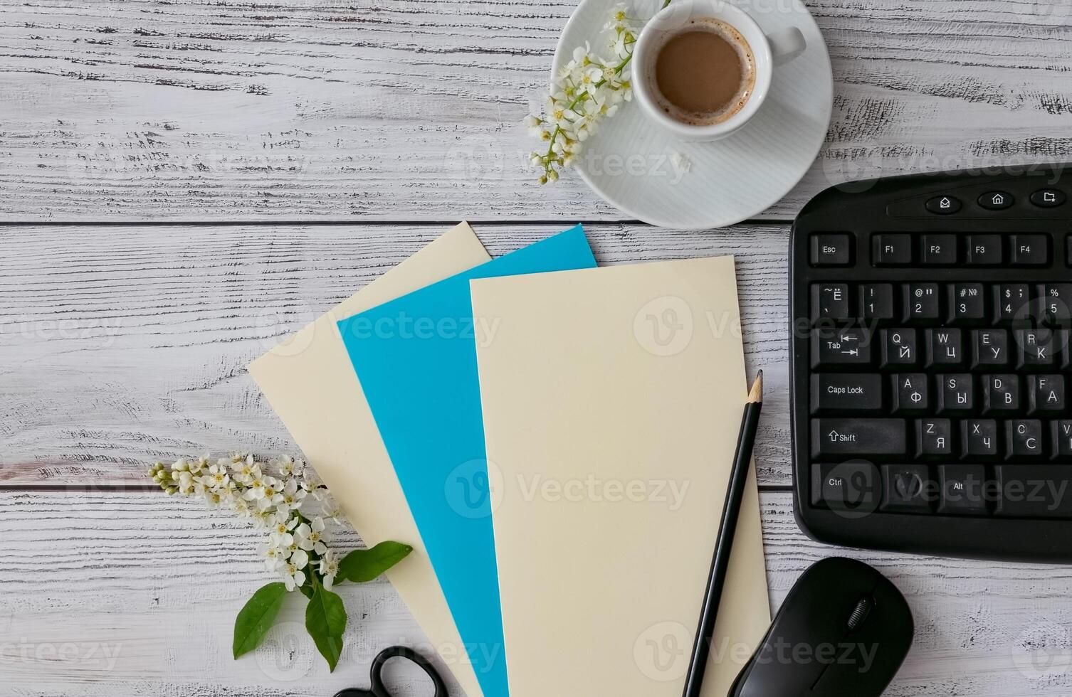 Workspace setup with coffee cup, notebook, pencil, and keyboard on wooden table photo