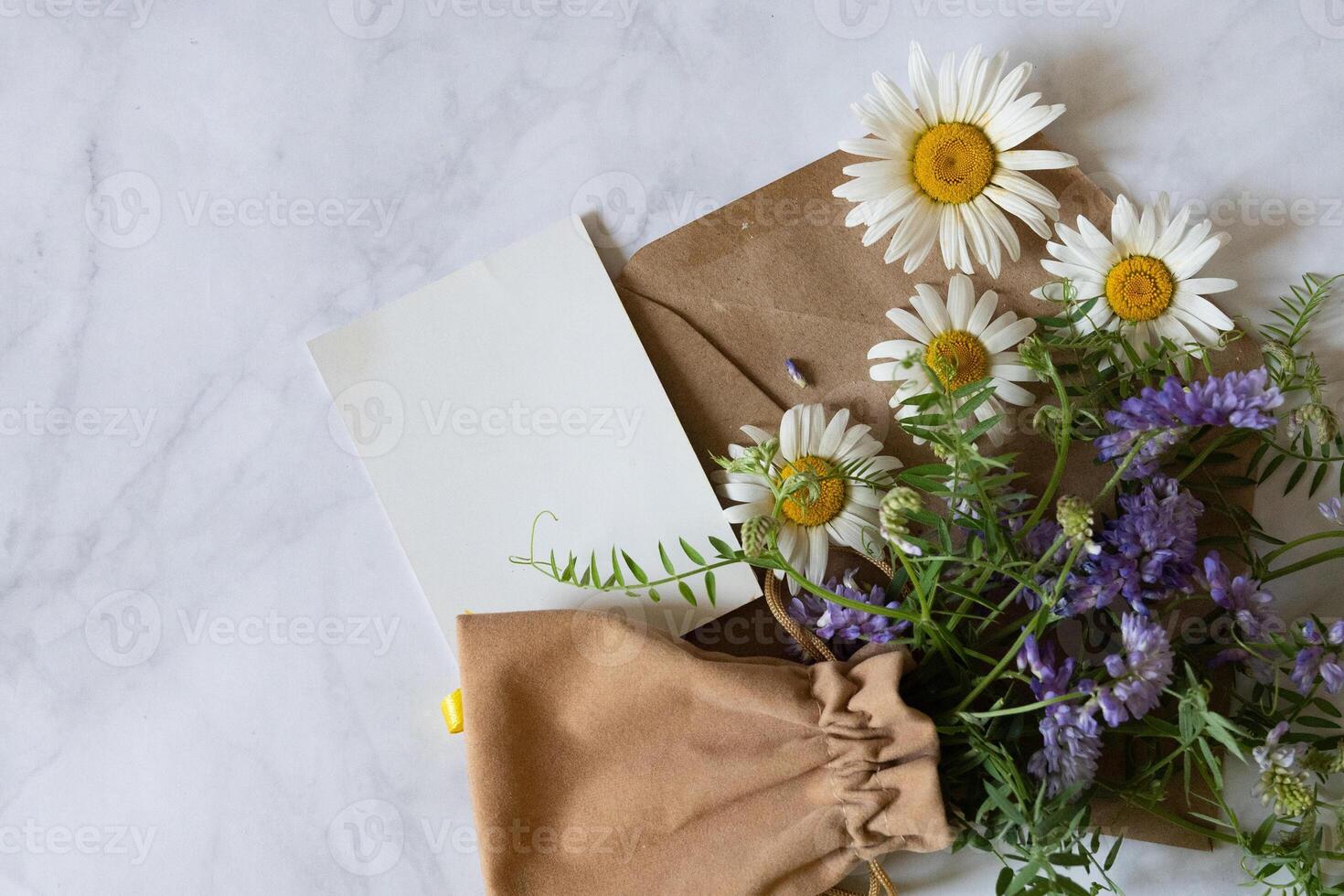 A top-down view reveals a cup of tea on a white saucer, with small white flowers and fresh green leaves artistically arranged around it, emphasizing simplicity and freshness. photo