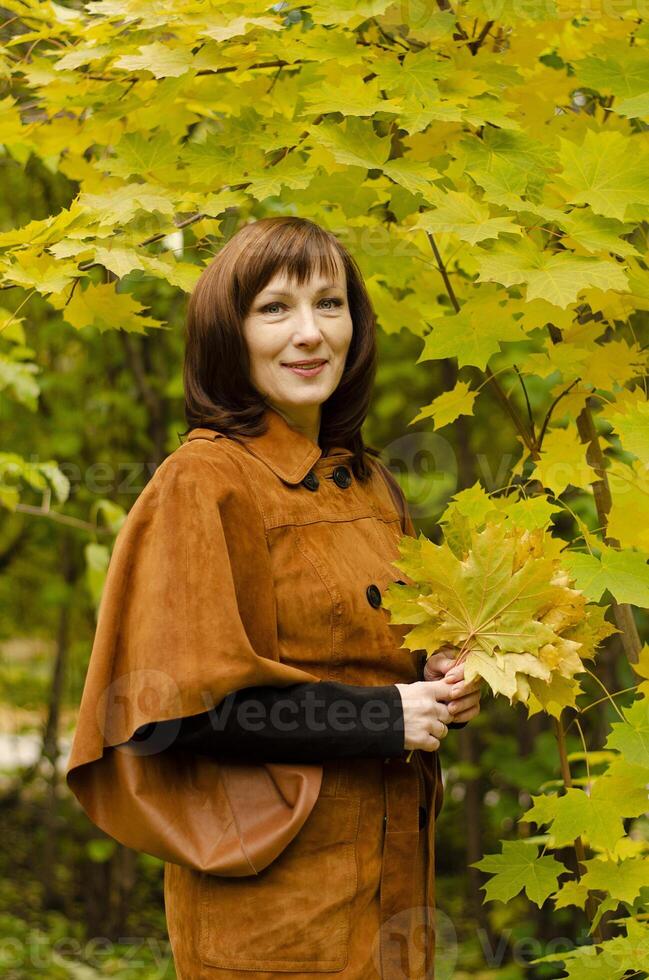 The person is dressed in a brown, vintage-style coat with large buttons and a belt, paired with black gloves. photo