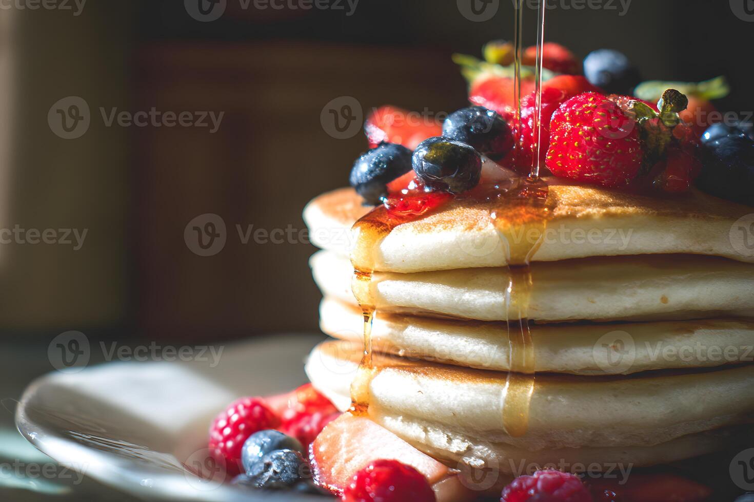 Stack of fluffy pancakes layered with fresh strawberries, blueberries, raspberries, and amber syrup photo