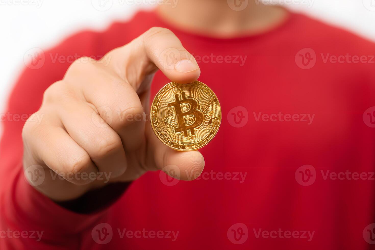 Person in red shirt holding shiny golden Bitcoin coin demonstrating digital currency concept photo