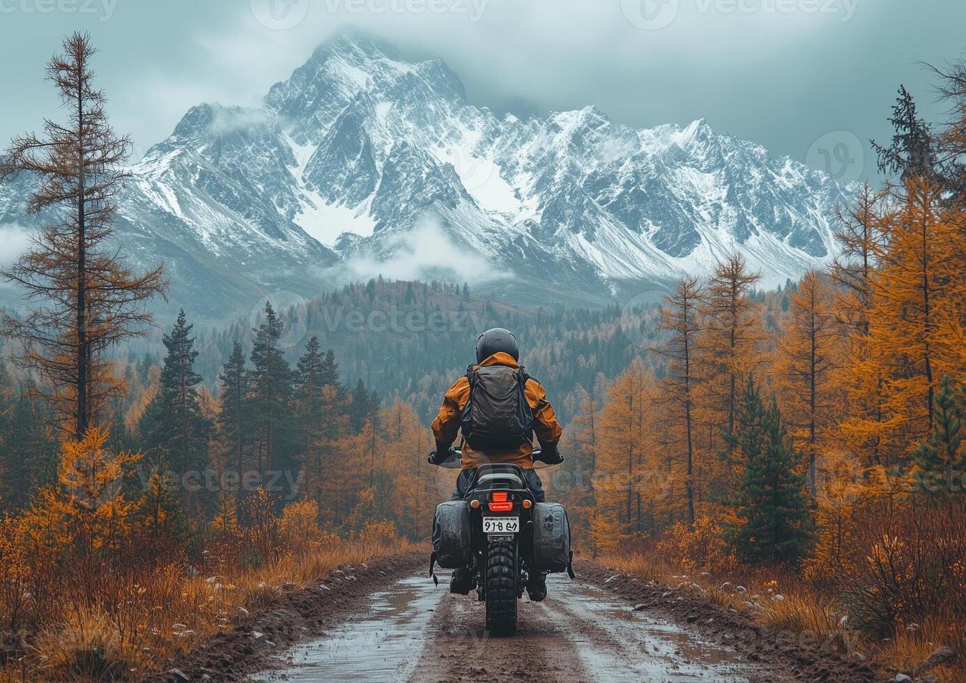 A man riding a motorcycle on a dirt road in the mountains photo
