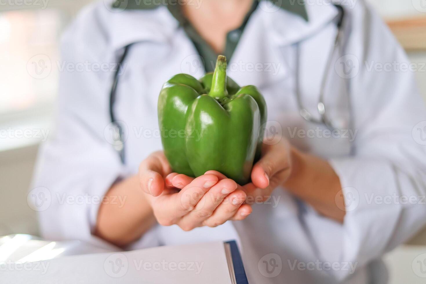 Doctor nutritionist showing green pepper Green vegetables help maintain heart health and improve digestion. Concept healthy eating, medical services. photo