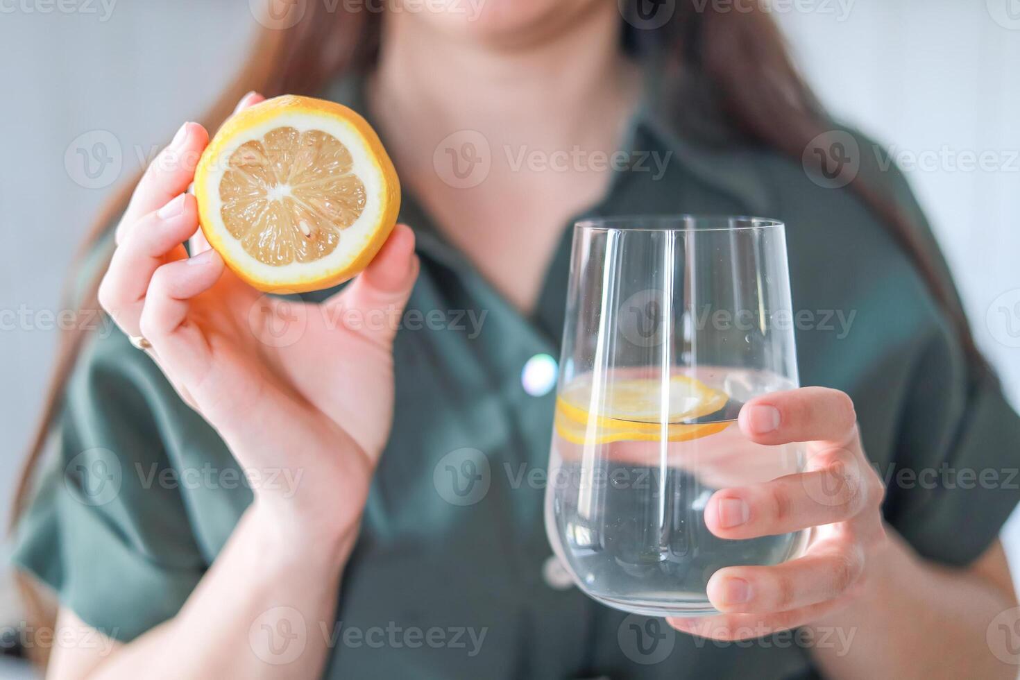 A woman holds a glass pitcher and a glass with water and lemon water with lemon helps improve digestion and maintains energy levels. Wellness concept, diet. photo