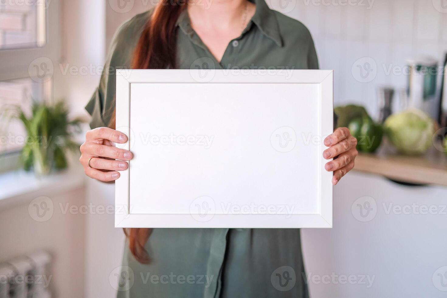 Mockup white blank canvas in hands of woman in kitchen. Space for text. Mock up design. Concept of dietetics, cooking, menu, recipes photo