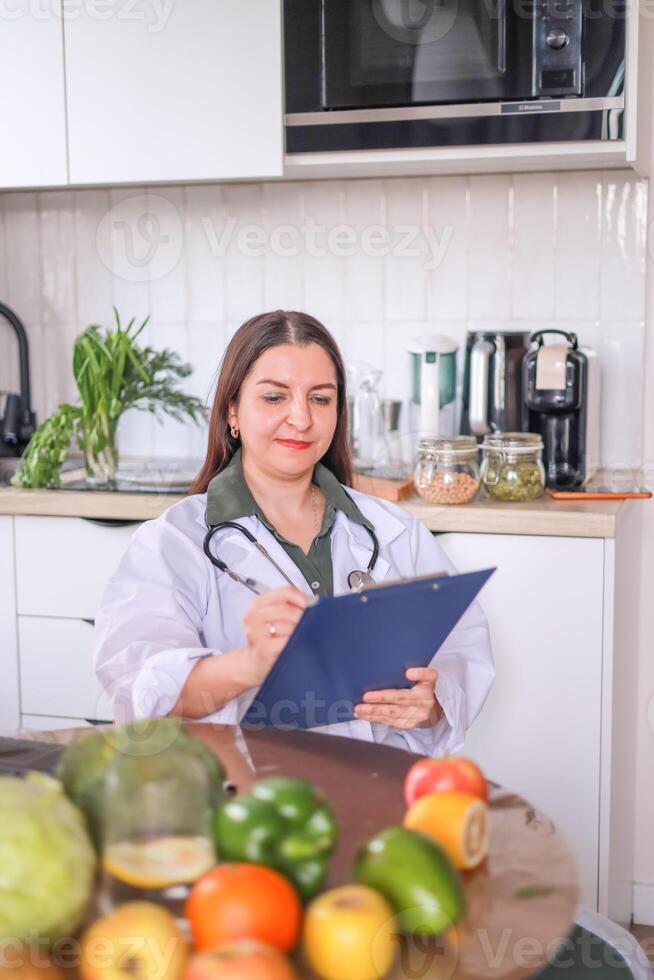 Nutritionist in a white coat working on a meal plan at a table with vegetables and fruits. Health, fitness concept. photo
