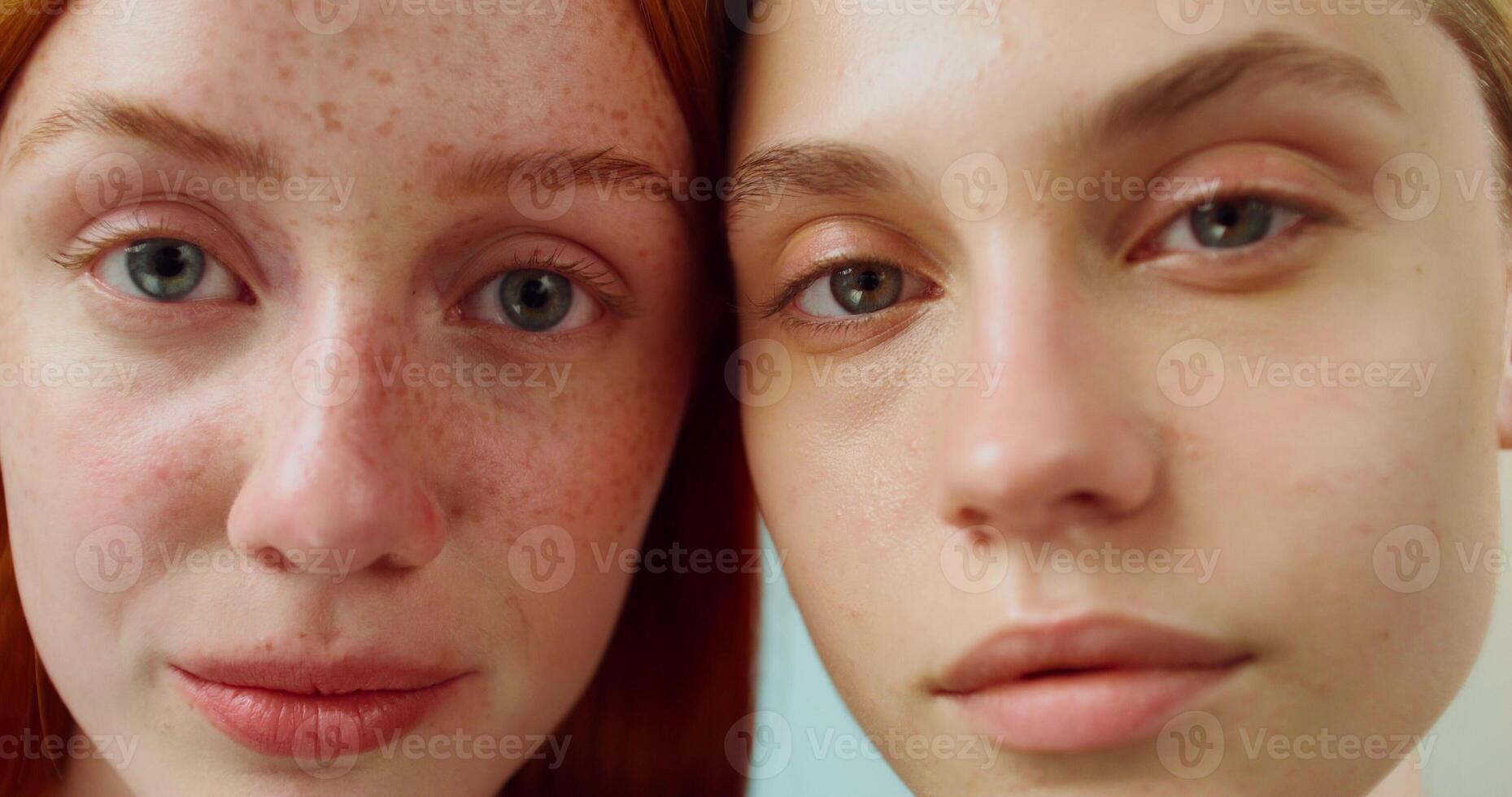 Two women look at the camera with a calm look, leaning their faces against each other. Studio . Close-up of their faces photo