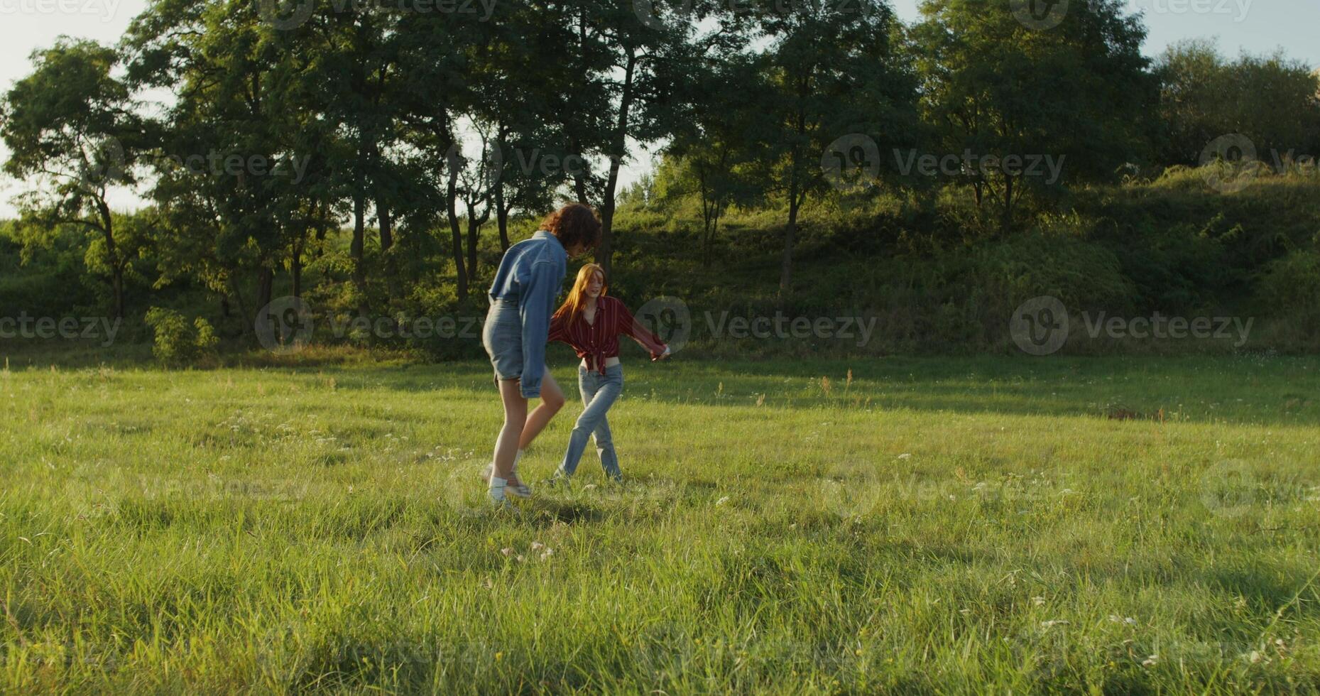 Two women are jumping and having fun standing in a meadow on a summer day. Summer holidays, carefree time photo