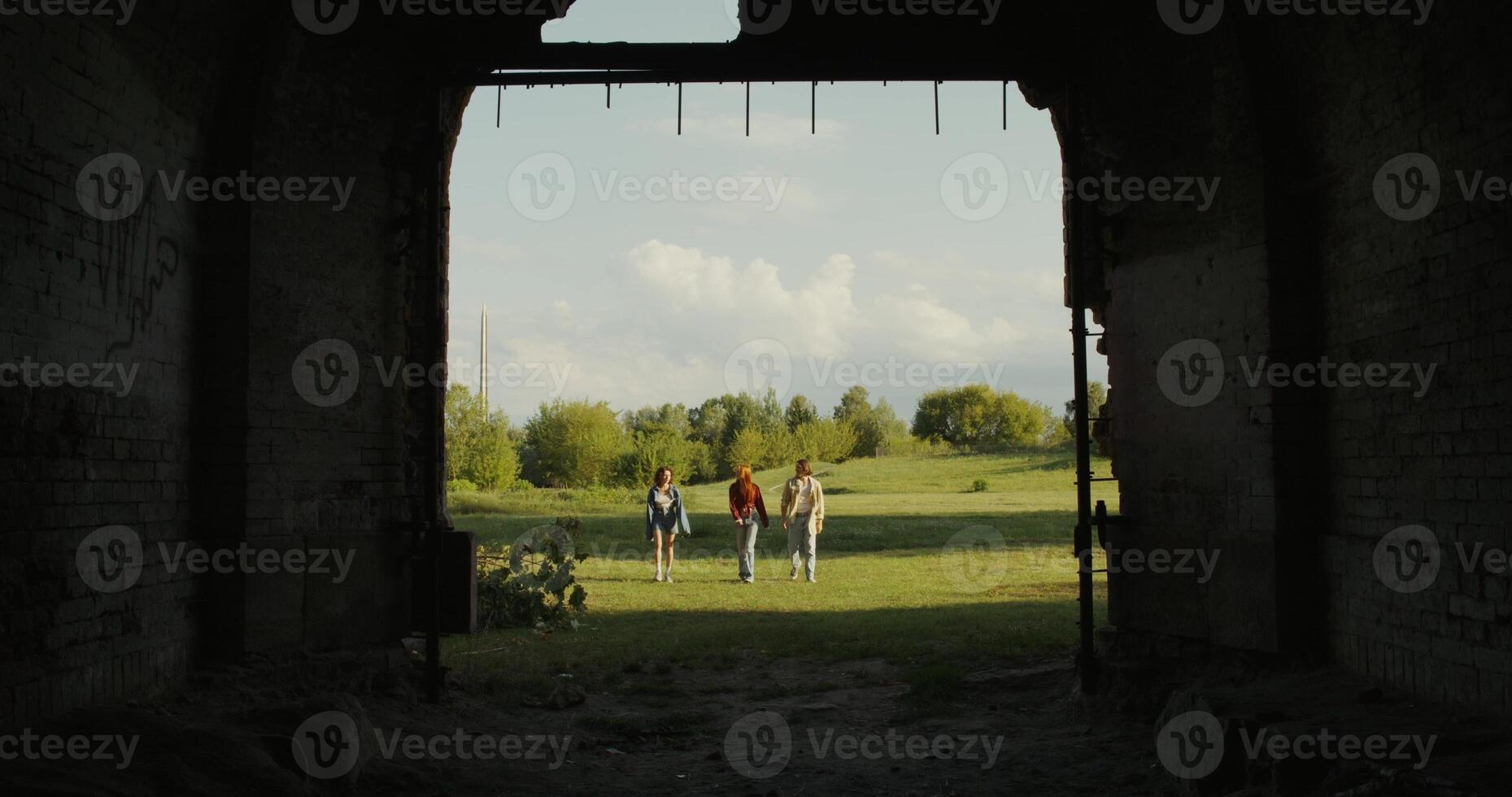 Three friends are walking near the ruins of a historic building. A sunny summer day photo